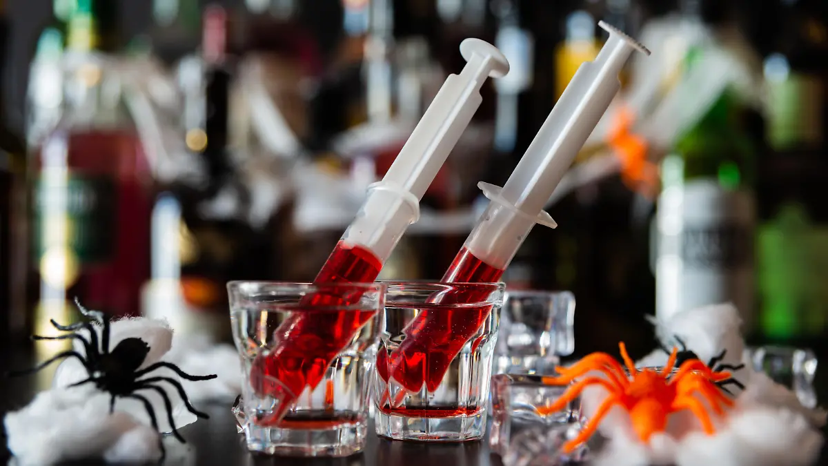 creepy halloween party cocktails with syringes of grenadine syrup as blood, shot drinks at party, scary bar