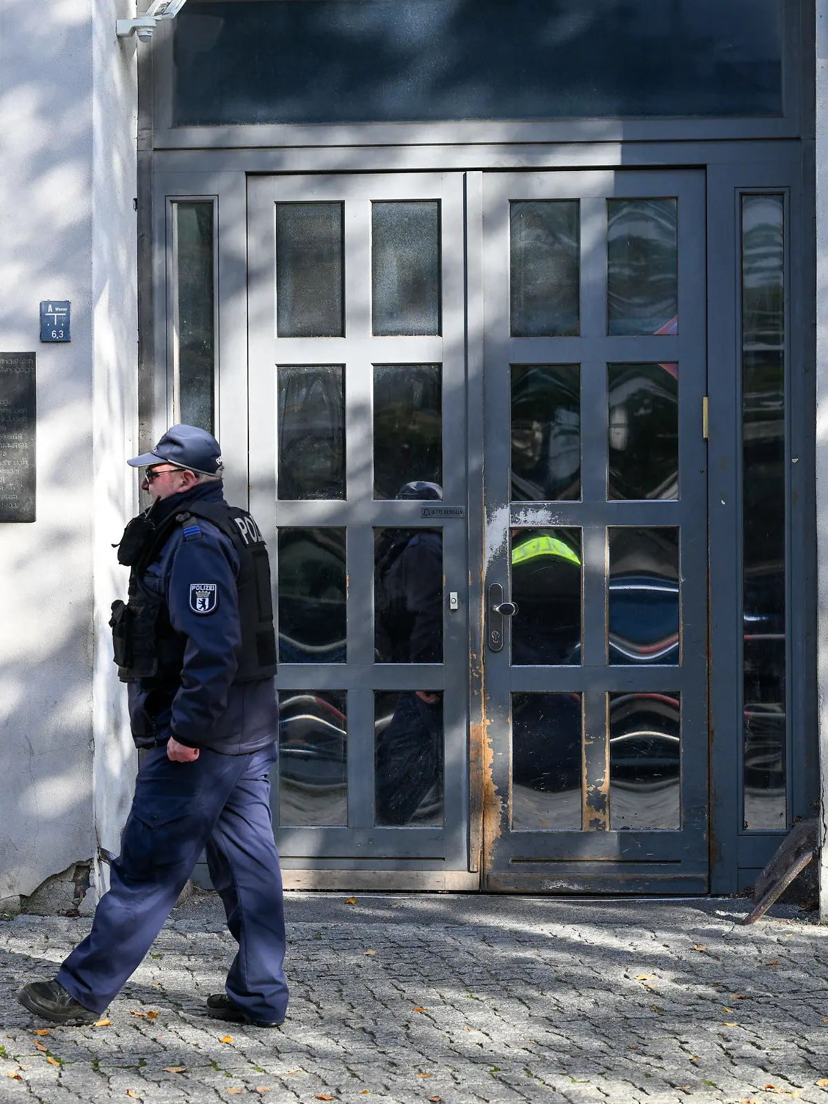 18.10.2023, Berlin: Ein Polizeibeamter geht an der Synagoge an der Brunnenstraße 33 in Berlin entlang, die Ziel eines Anschlags war. Nach dem versuchten Brandanschlag auf eine Synagoge in Berlin haben am Mittwoch Politikerinnen und Politiker mit Entsetzen reagiert und mehr Engagement gegen Antisemitismus gefordert.  Nach dem versuchten Brandanschlag auf eine Synagoge in Berlin hat die Generalstaatsanwaltschaft der Hauptstadt die Ermittlungen an sich gezogen. Foto: Soeren Stache/dpa +++ dpa-Bildfunk +++