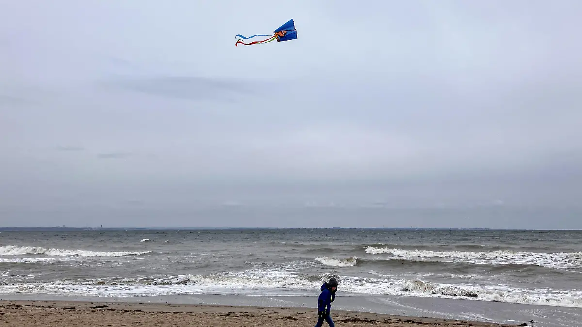 19.10.2023, Schleswig-Holstein, Niendorf: Ein Junge lässt seinen Drachen an der Ostseeküste fliegen. Die Menschen an der schleswig-holsteinischen Ostseeküste müssen sich auf eine schwere Sturmflut einstellen. Foto: Thomas Müller/dpa +++ dpa-Bildfunk +++
