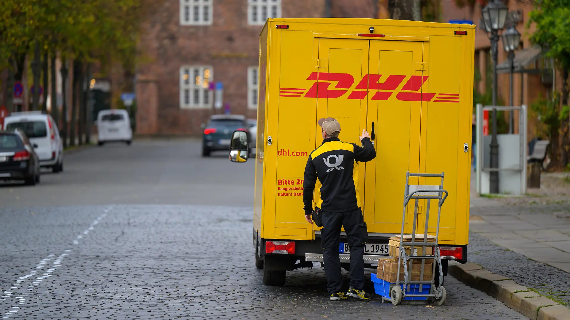 03.11.2022, Niedersachsen, Lüneburg: Ein Zusteller entlädt ein Fahrzeug von DHL in der Innenstadt. Foto: Philipp Schulze/dpa +++ dpa-Bildfunk +++