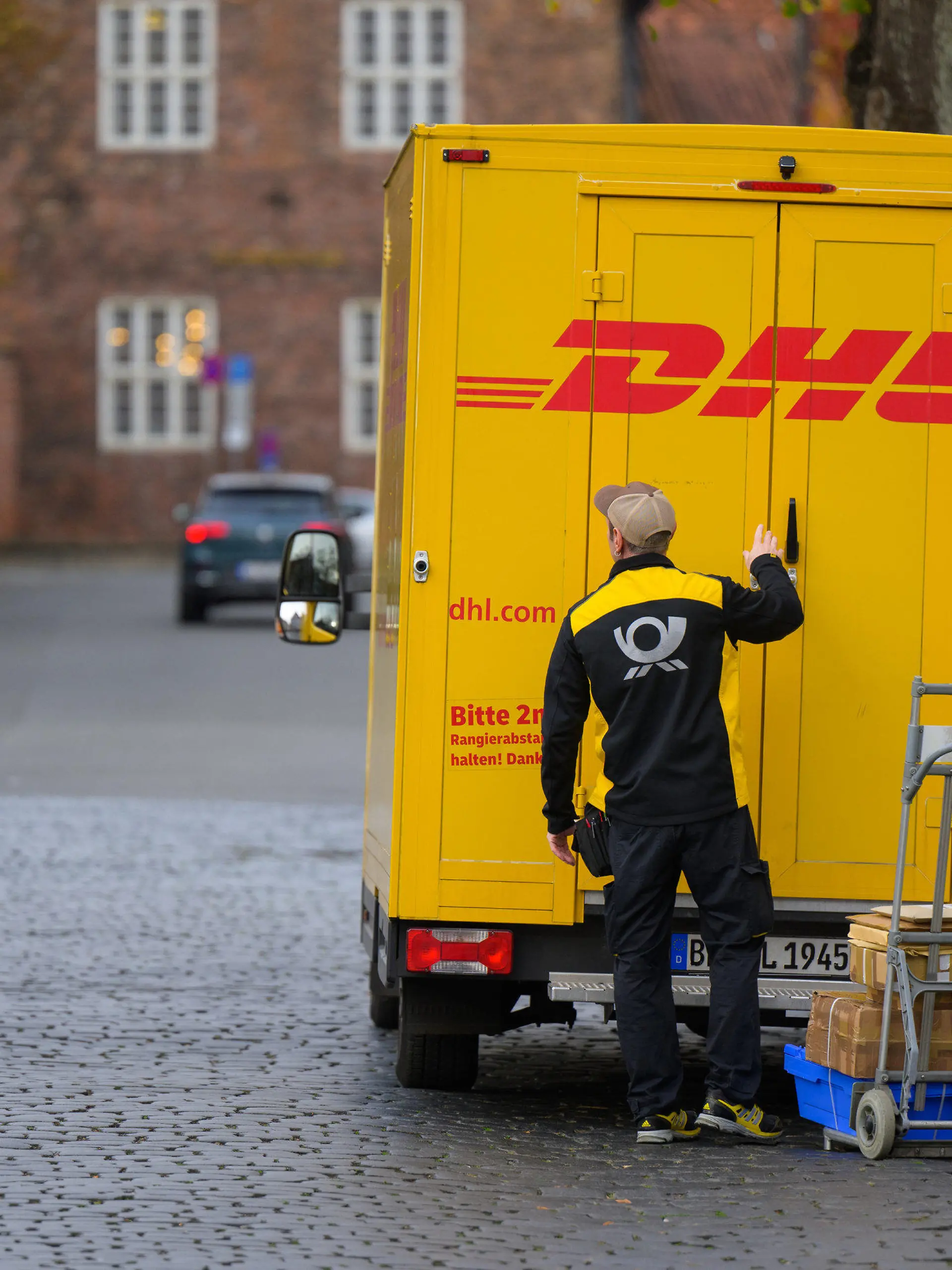 03.11.2022, Niedersachsen, Lüneburg: Ein Zusteller entlädt ein Fahrzeug von DHL in der Innenstadt. Foto: Philipp Schulze/dpa +++ dpa-Bildfunk +++
