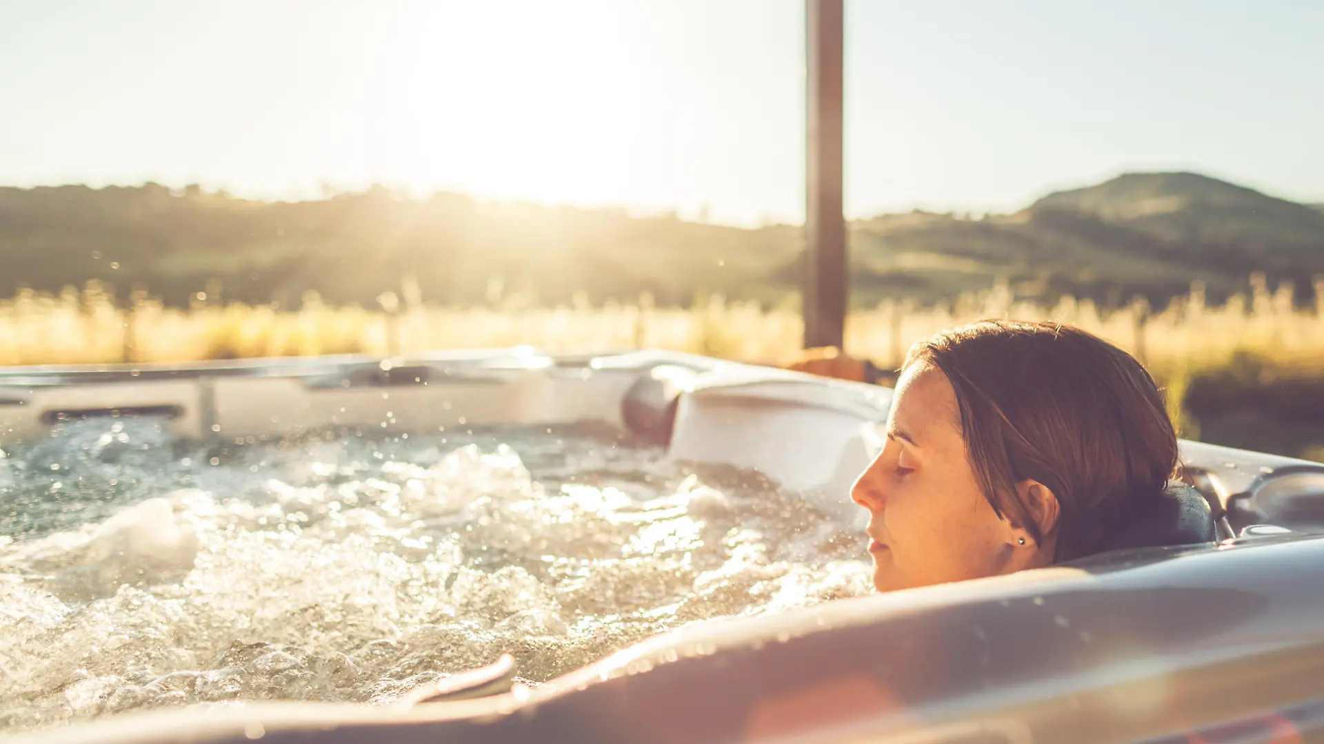 Woman in whirlpool hot tub at sunset