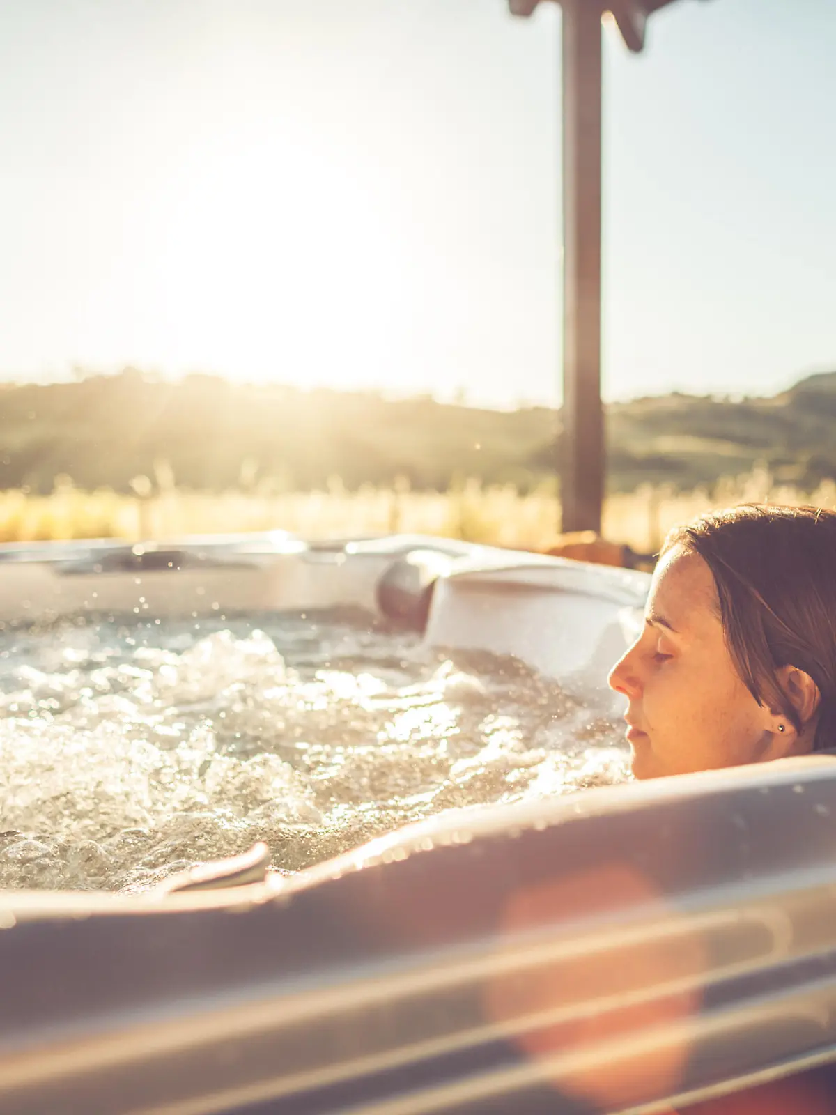 Woman in whirlpool hot tub at sunset