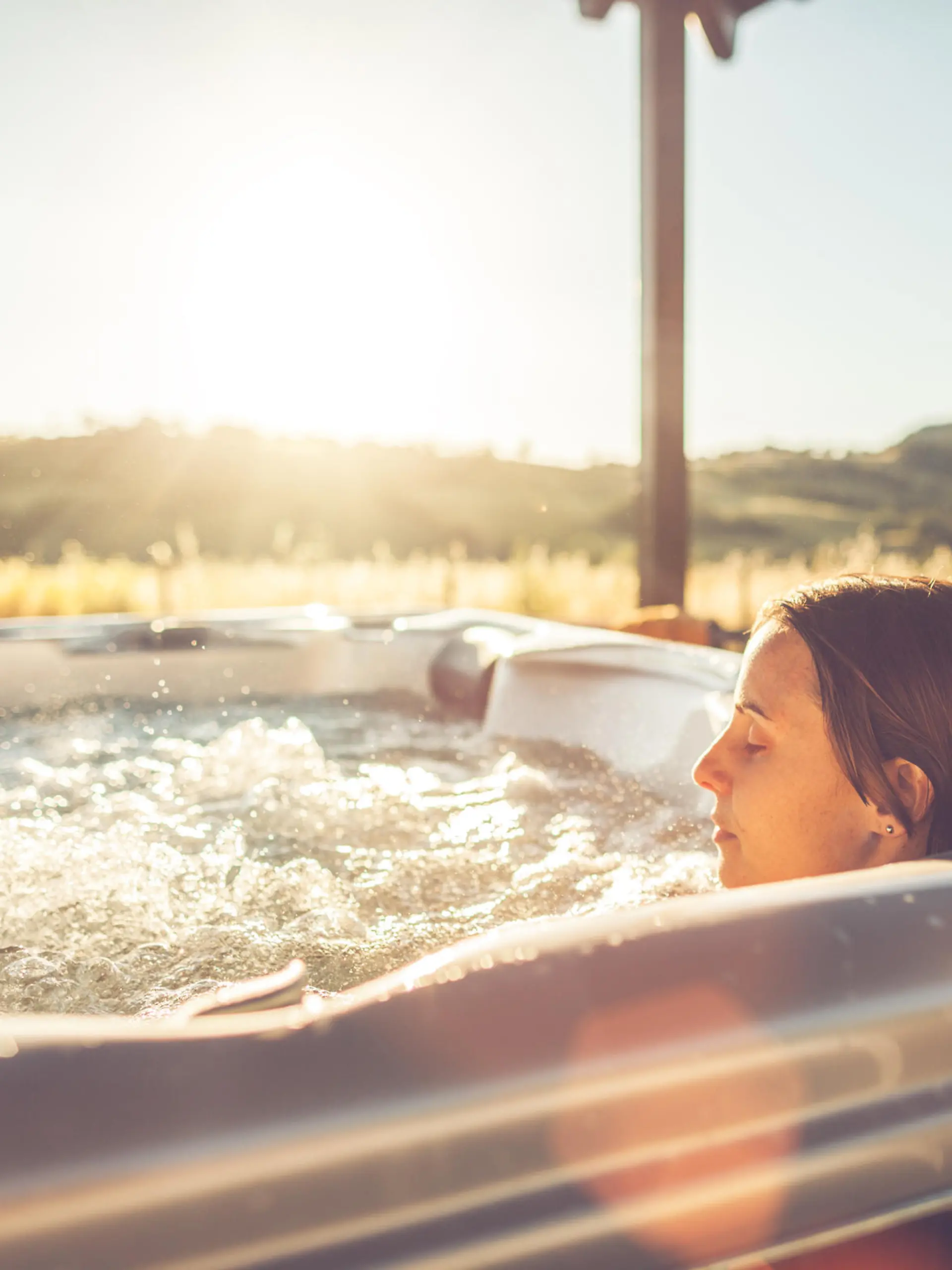Woman in whirlpool hot tub at sunset