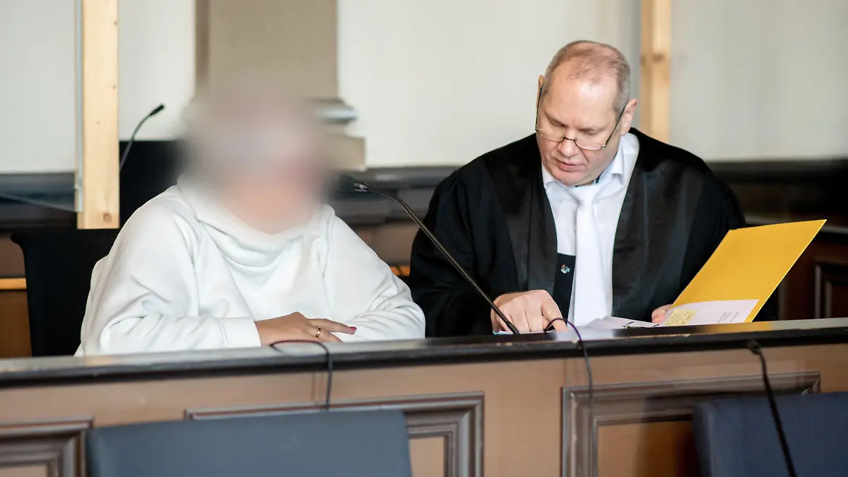 07.11.2022, Niedersachsen, Verden: Die angeklagte Frau sitzt vor Prozessbeginn neben ihrem Anwalt Thorsten Osterkamp in einem Gerichtssaal im Landgericht Verden. Die Hebamme ist wegen Körperverletzung mit Todesfolge angeklagt. Sie betreute im Januar 2015 eine schwangere Frau während einer mehrtägigen Hausgeburt, bei der es zu Komplikationen gekommen ist. Dabei soll die Hebamme erkannt haben, dass es der schwangeren Frau und dem Baby zunehmend schlechter gegangen sei und das Leben des Babys ohne ärztliche Hilfe gefährdet sein könnte. Foto: Hauke-Christian Dittrich/dpa - ACHTUNG: Person(en) wurde(n) aus rechtlichen Gründen gepixelt +++ dpa-Bildfunk +++