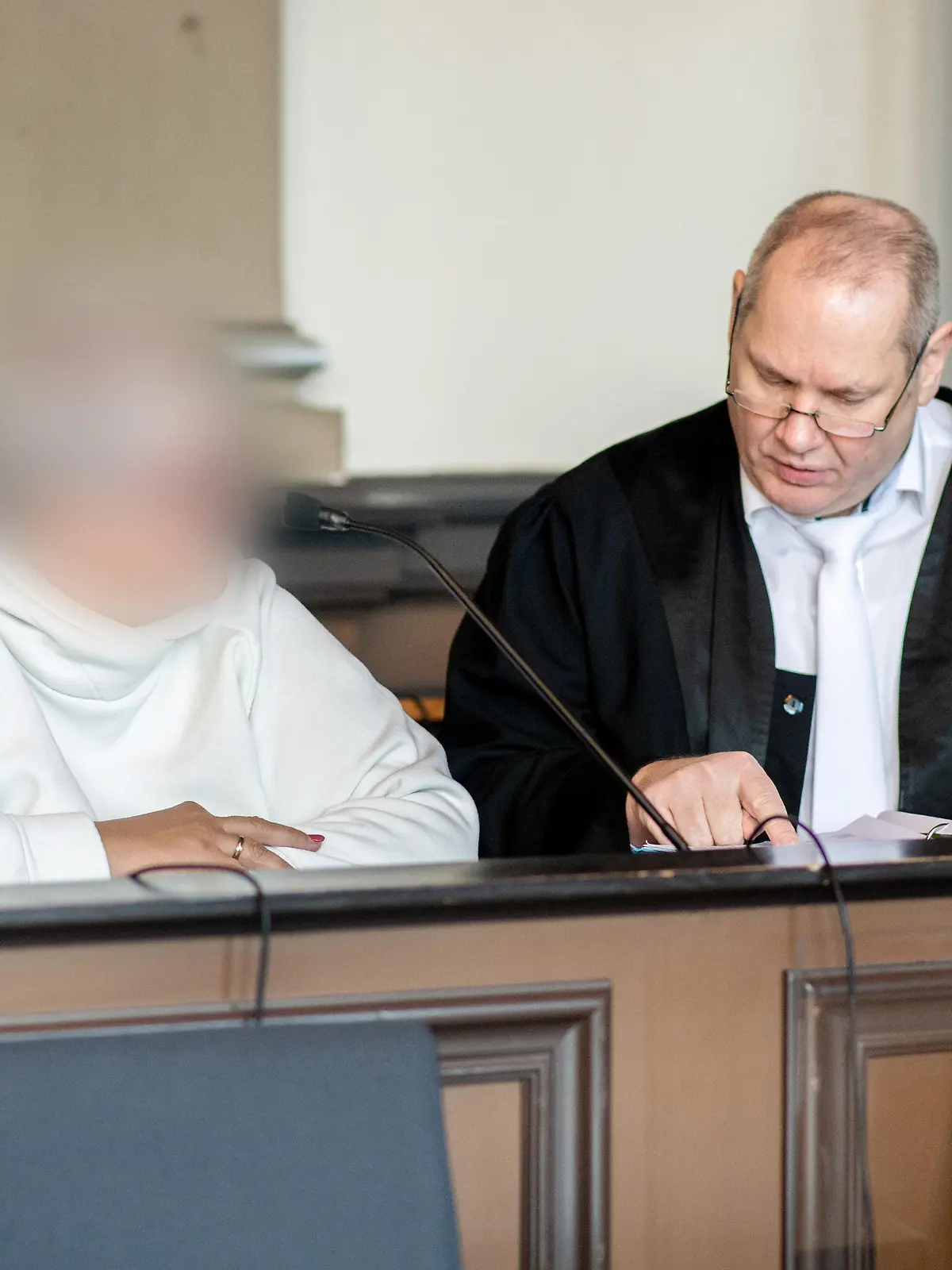 07.11.2022, Niedersachsen, Verden: Die angeklagte Frau sitzt vor Prozessbeginn neben ihrem Anwalt Thorsten Osterkamp in einem Gerichtssaal im Landgericht Verden. Die Hebamme ist wegen Körperverletzung mit Todesfolge angeklagt. Sie betreute im Januar 2015 eine schwangere Frau während einer mehrtägigen Hausgeburt, bei der es zu Komplikationen gekommen ist. Dabei soll die Hebamme erkannt haben, dass es der schwangeren Frau und dem Baby zunehmend schlechter gegangen sei und das Leben des Babys ohne ärztliche Hilfe gefährdet sein könnte. Foto: Hauke-Christian Dittrich/dpa - ACHTUNG: Person(en) wurde(n) aus rechtlichen Gründen gepixelt +++ dpa-Bildfunk +++