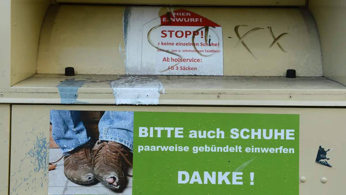 ARCHIV - Ein Kleidercontainer wirbt am 30.11.2012 in Berlin mit einem Foto von abgetragenen Schuhen um den Einwurf von Schuhen. Foto: Jens Kalaene/dpa (zu dpa: "Falsche Wohltäter im Konkurrenzkampf um Altkleider") +++(c) dpa - Bildfunk+++