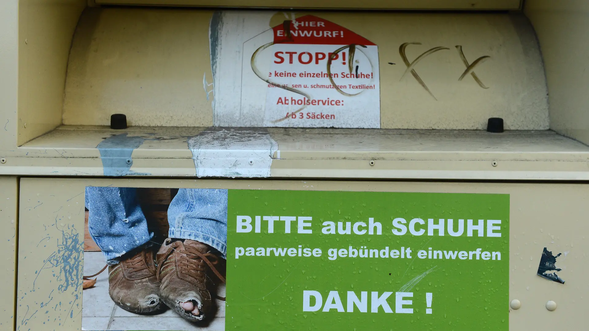 ARCHIV - Ein Kleidercontainer wirbt am 30.11.2012 in Berlin mit einem Foto von abgetragenen Schuhen um den Einwurf von Schuhen. Foto: Jens Kalaene/dpa (zu dpa: "Falsche Wohltäter im Konkurrenzkampf um Altkleider") +++(c) dpa - Bildfunk+++