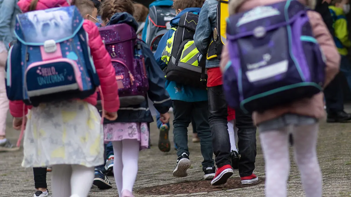 ARCHIV - 18.08.2021, Nordrhein-Westfalen, Wuppertal: Erstklässler mit ihren Schultaschen warten bei der Einschulung auf den gemeinsamen Gang in ihr Klassenzimmer. Die Grundschulklassen sind in Nordrhein-Westfalen so groß wie in keinem anderen Bundesland. Der Landtag debattiert am Donnerstag über die Konsequenzen. (Zu dpa: «Landtag debattiert über volle Klassenzimmer in Grundschulen») Foto: Bernd Thissen/dpa +++ dpa-Bildfunk +++