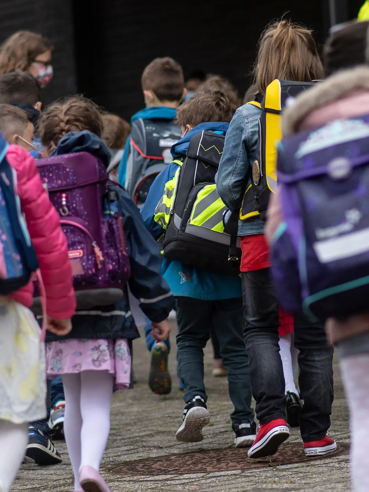 ARCHIV - 18.08.2021, Nordrhein-Westfalen, Wuppertal: Erstklässler mit ihren Schultaschen warten bei der Einschulung auf den gemeinsamen Gang in ihr Klassenzimmer. Die Grundschulklassen sind in Nordrhein-Westfalen so groß wie in keinem anderen Bundesland. Der Landtag debattiert am Donnerstag über die Konsequenzen. (Zu dpa: «Landtag debattiert über volle Klassenzimmer in Grundschulen») Foto: Bernd Thissen/dpa +++ dpa-Bildfunk +++