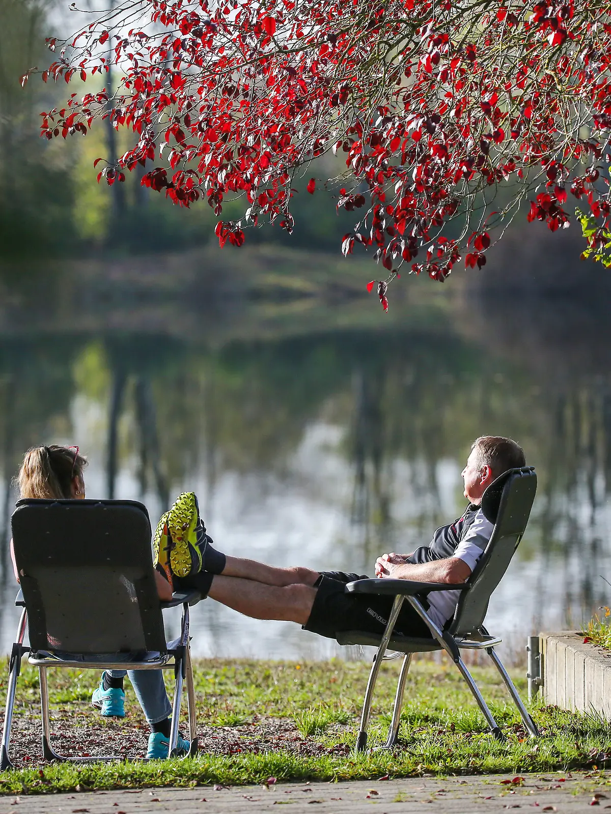 29.10.2022, Baden-Württemberg, Ertingen: Ein Mann und eine Frau sitzen bei sommerlichen Temperaturen an einem Badesee in der Sonne. Foto: Thomas Warnack/dpa +++ dpa-Bildfunk +++