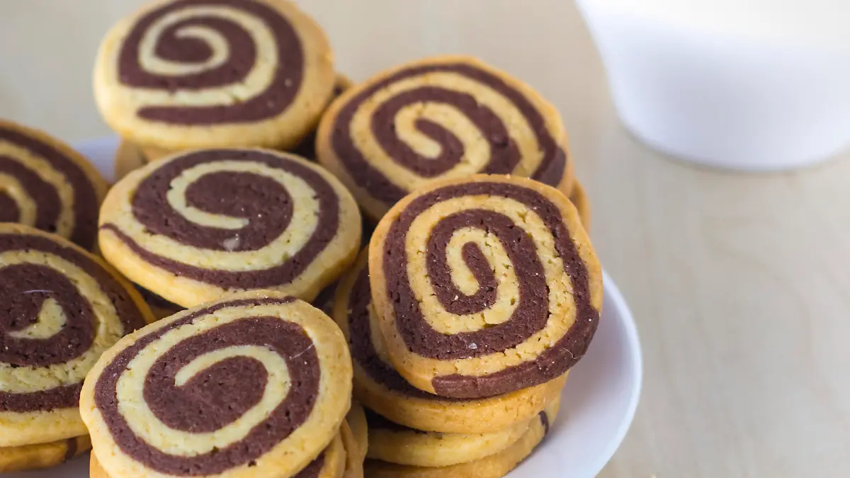 Stack of sprinkled cookies and cup of milk on table