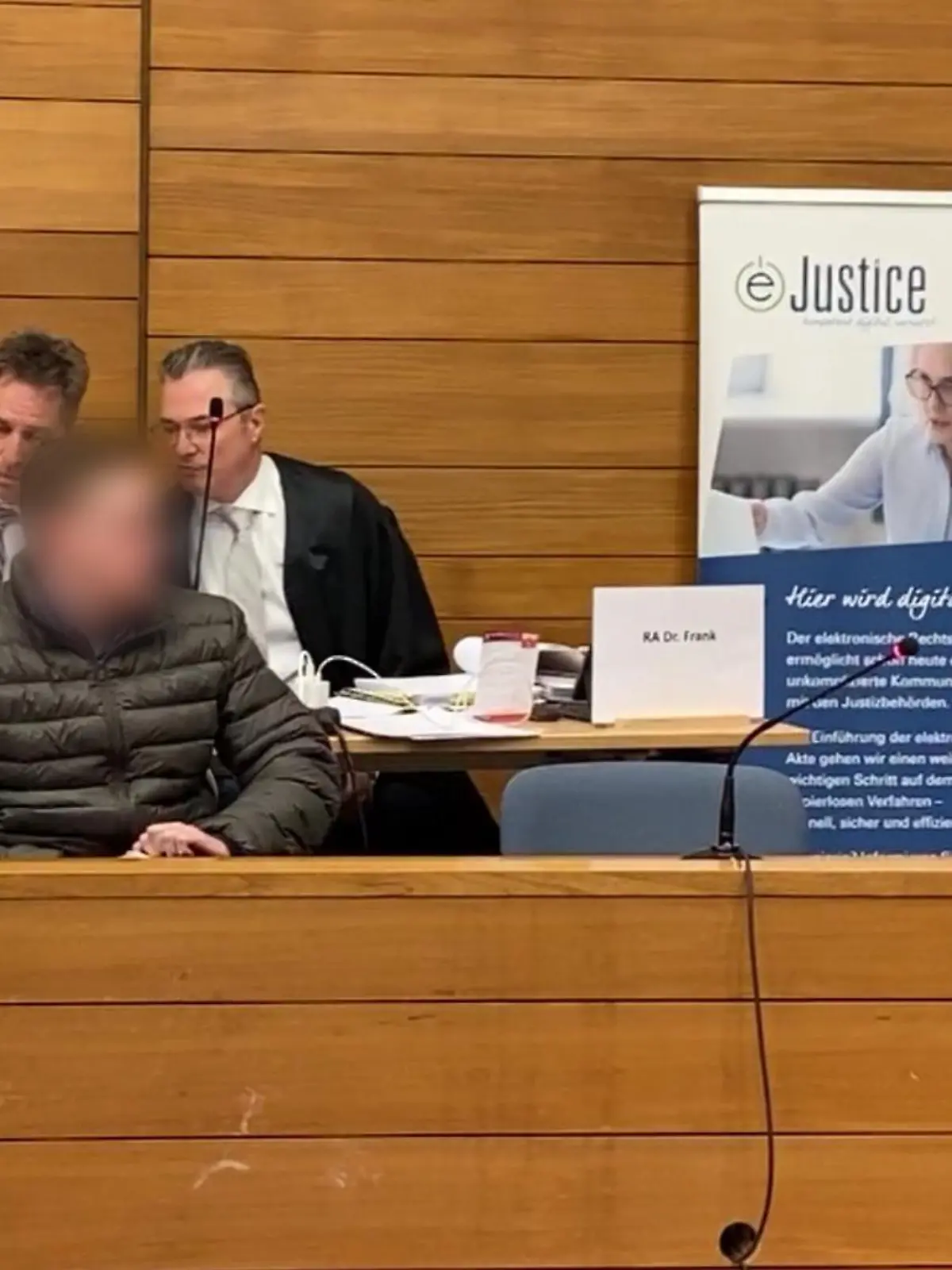 Der Angeklagte sitzt auf der Anklagebank. Dahinter seine Verteidiger.