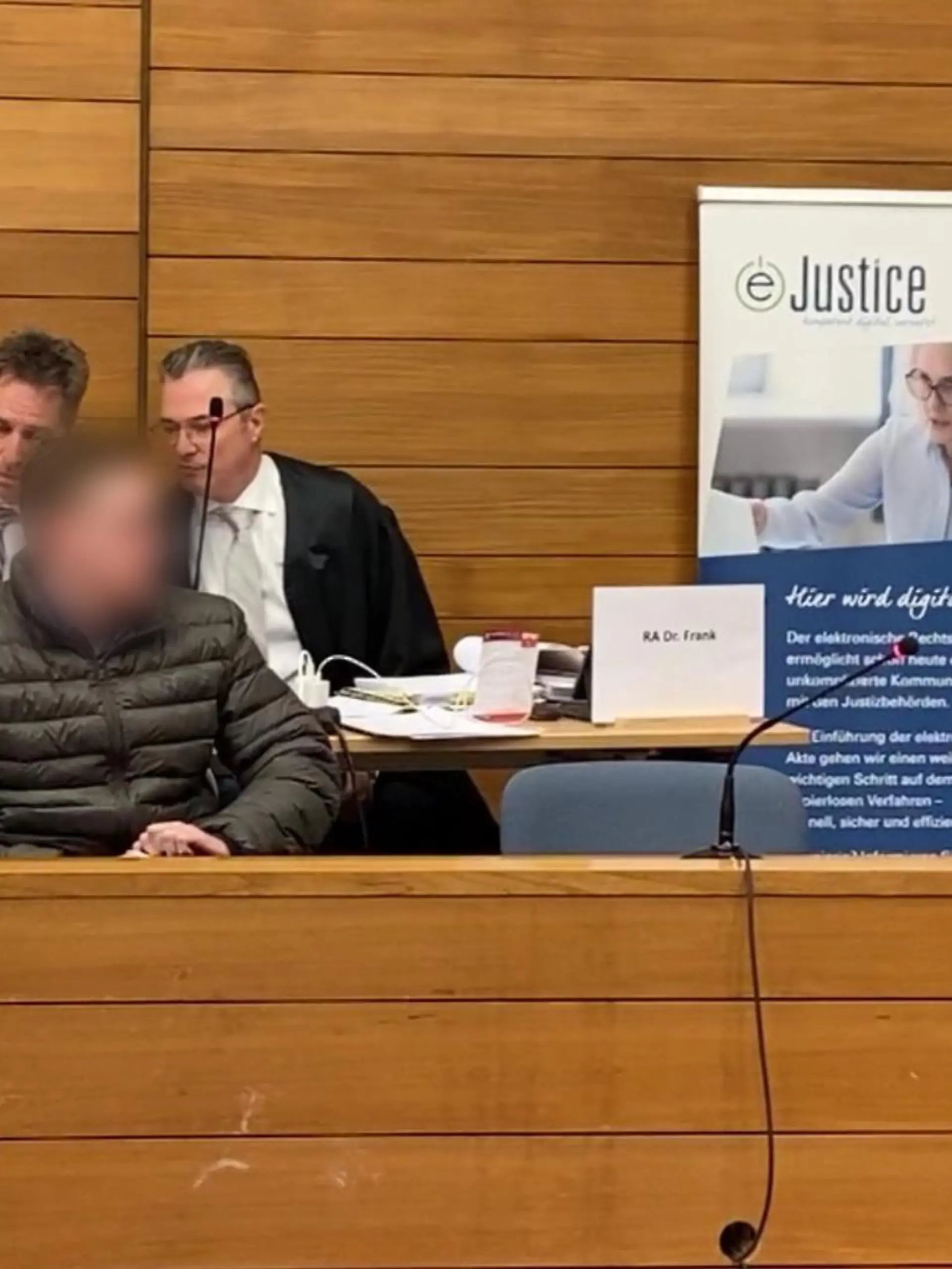 Der Angeklagte sitzt auf der Anklagebank. Dahinter seine Verteidiger.