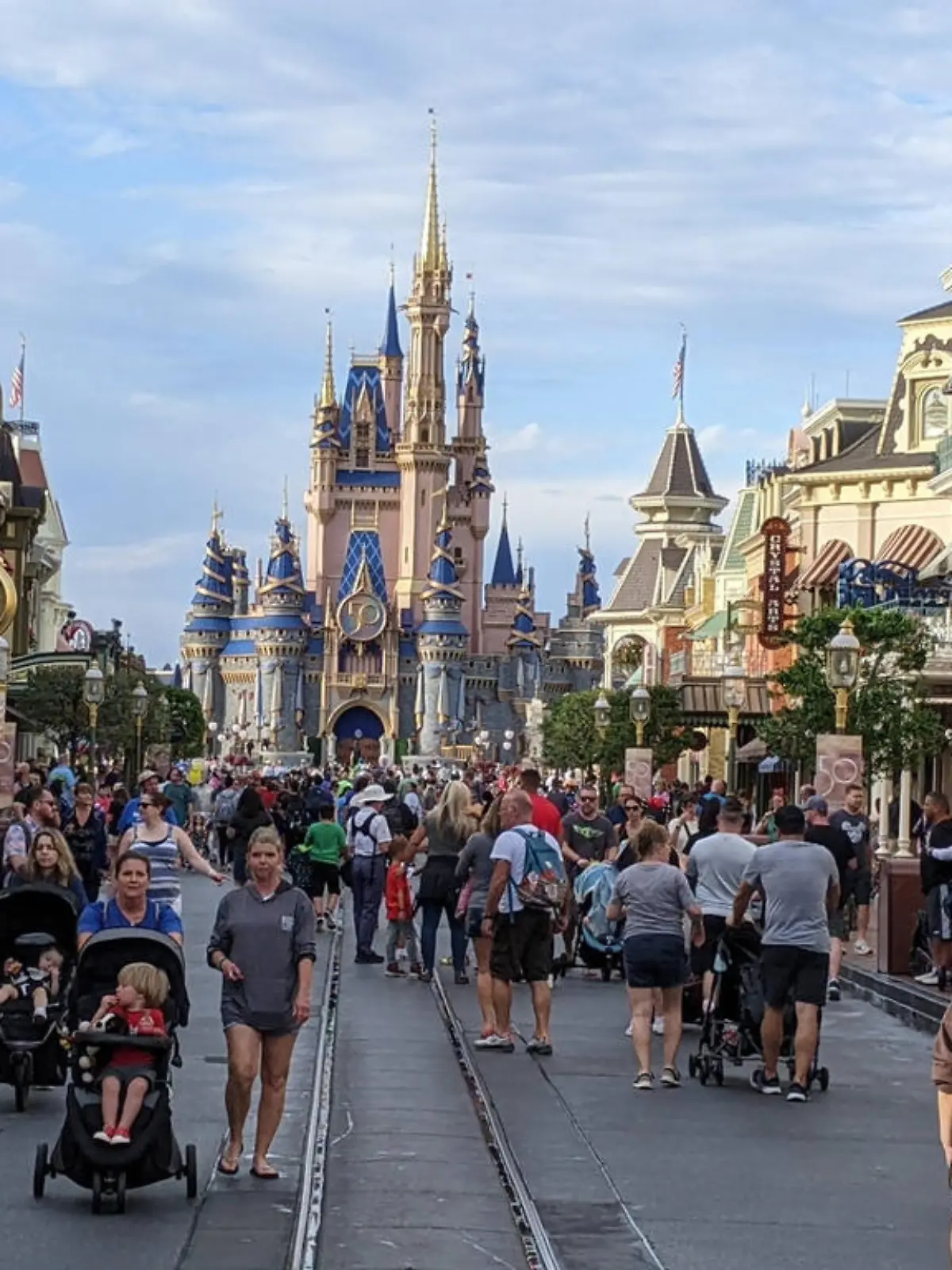 Visitors on Main Street, Magic Kingdom,  Walt Disney World, Orlando, Florida. Cinderella's Castle at rear is decorated for the 50th anniversary of the parks's opening.