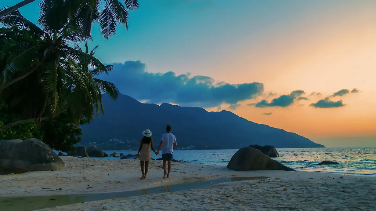 A couple of men and women watching the sunset o a tropical beach at the Seychelles Islands.