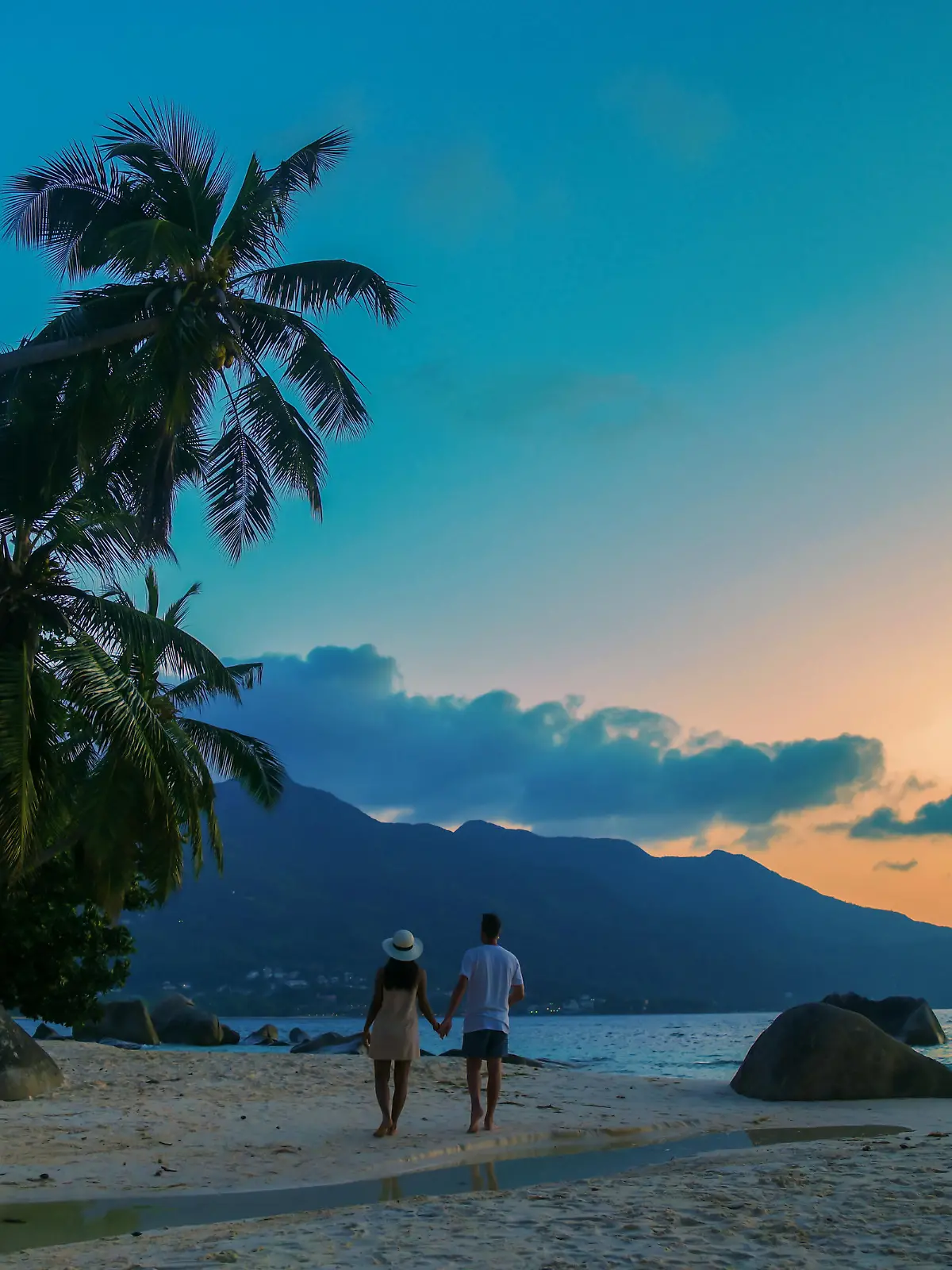 A couple of men and women watching the sunset o a tropical beach at the Seychelles Islands.