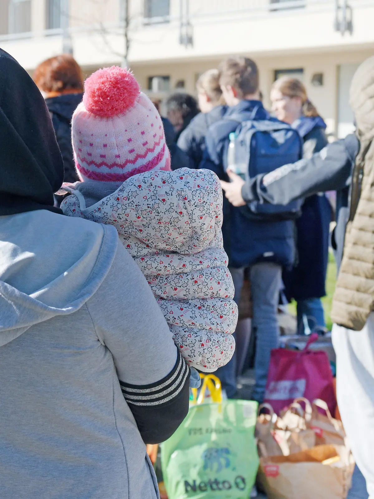 ARCHIV - 03.03.2022, Nordrhein-Westfalen, Köln: Geflüchtete aus der Ukraine stehen vor den Gebäuden einer Flüchtlingsunterkunft. Nordrhein-Westfalen plant derzeit nicht, Bezahlkarten einzuführen, um Bargeld-Leistungen für Asylbewerber zu ersetzen.     (zu dpa «NRW plant keine Bezahlkarten für Flüchtlinge: "Persönlichkeitsrechte"»). Foto: Henning Kaiser/dpa +++ dpa-Bildfunk +++