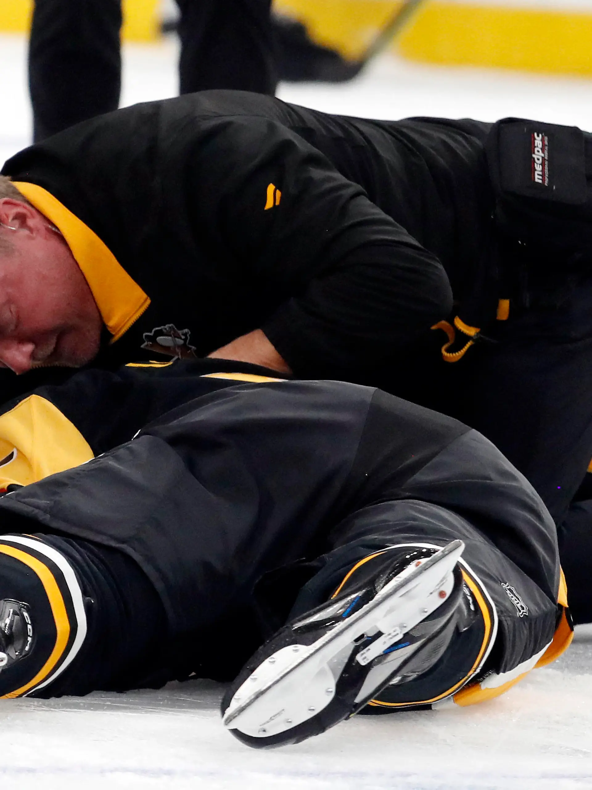 Oct 24, 2023; Pittsburgh, Pennsylvania, USA;  Pittsburgh Penguins trainer Chris Stewart (top) tends to defenseman John Ludvig (7) after Ludvig was injured on a check against the Dallas Stars during the second period at PPG Paints Arena. Mandatory Credit: Charles LeClaire-USA TODAY Sports