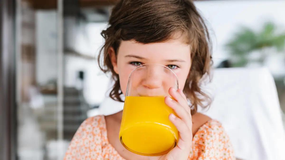 Preschool brown haired girl looking at camera while drinking tasty orange juice from glass in cafeteria HodeiUnzueta_ID936_34706_013 Copyright: xHodeixUnzuetax