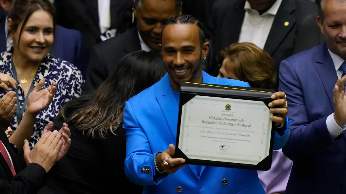 07.11.2022, Brasilien, Brasilia: Lewis Hamilton (M), Rennfahrer aus Großbritannien, präsentiert seinen Titel als Ehrenbürger Brasiliens. Nach seinem Sieg in Interlagos in der Vorsaison feierte Hamilton mit einer brasilianischen Fahne auf dem Podium, was den Kongressabgeordneten Figueiredo dazu veranlasste ihn als Ehrenbürger vorzuschlagen. Foto: Eraldo Peres/AP/dpa +++ dpa-Bildfunk +++