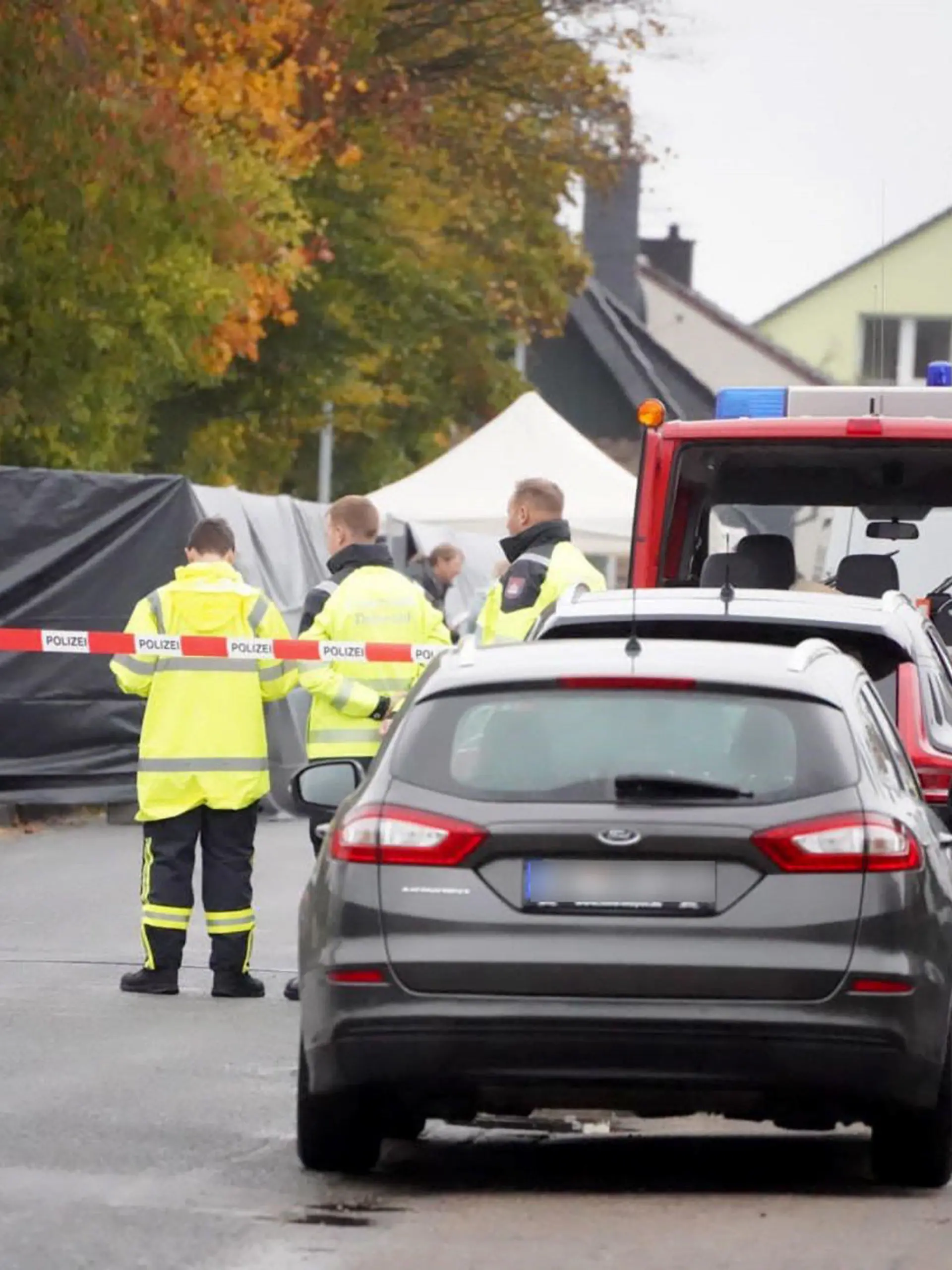 26.10.2023, Nordrhein-Westfalen, Horn-Bad Meinberg: Ermittler stehen in einem von der Polizei abgesperrten Bereich, nachdem eine Leiche gefunden wurde. Nach dem Fund einer männlichen Leiche in Horn-Bad Meinberg im Kreis Lippe ermittelt eine Mordkommission. (zu dpa «Toter auf Wiese gefunden - Polizei geht von Gewaltverbrechen aus») Foto: Christian Müller/Westfalennews/dpa - ACHTUNG: Nummernschild wurde aus rechtlichen Gründen gepixelt +++ dpa-Bildfunk +++