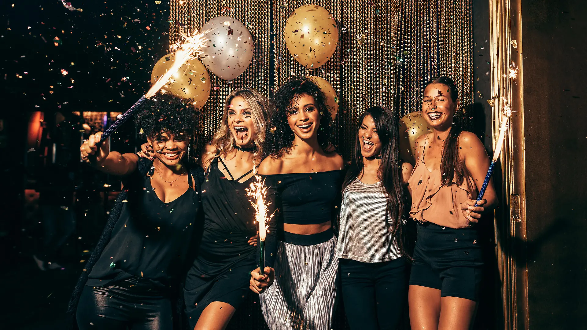 Shot of group of young women celebrating new years eve at the pub. Group of female friends with sparklers partying in nightclub.