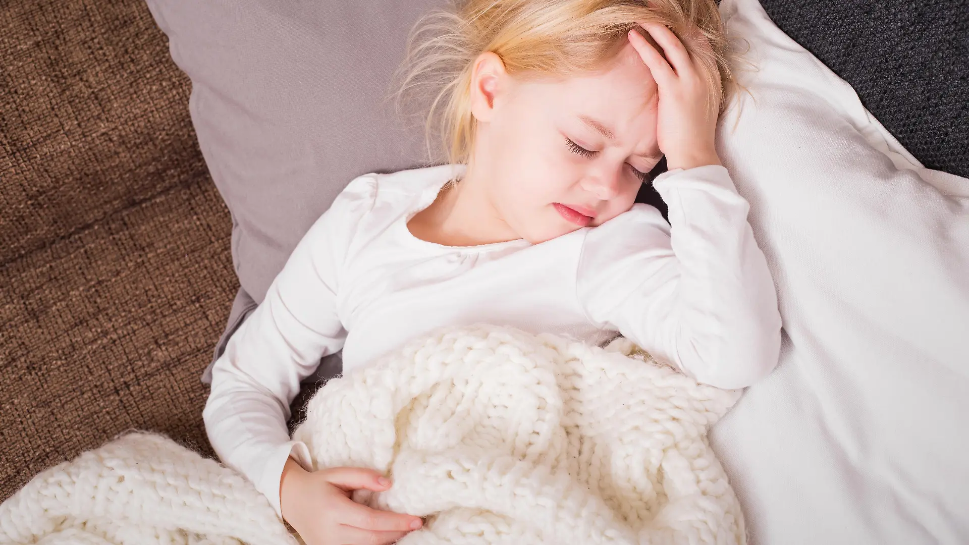 Little child being sick and holding her hand pressed against her forehead