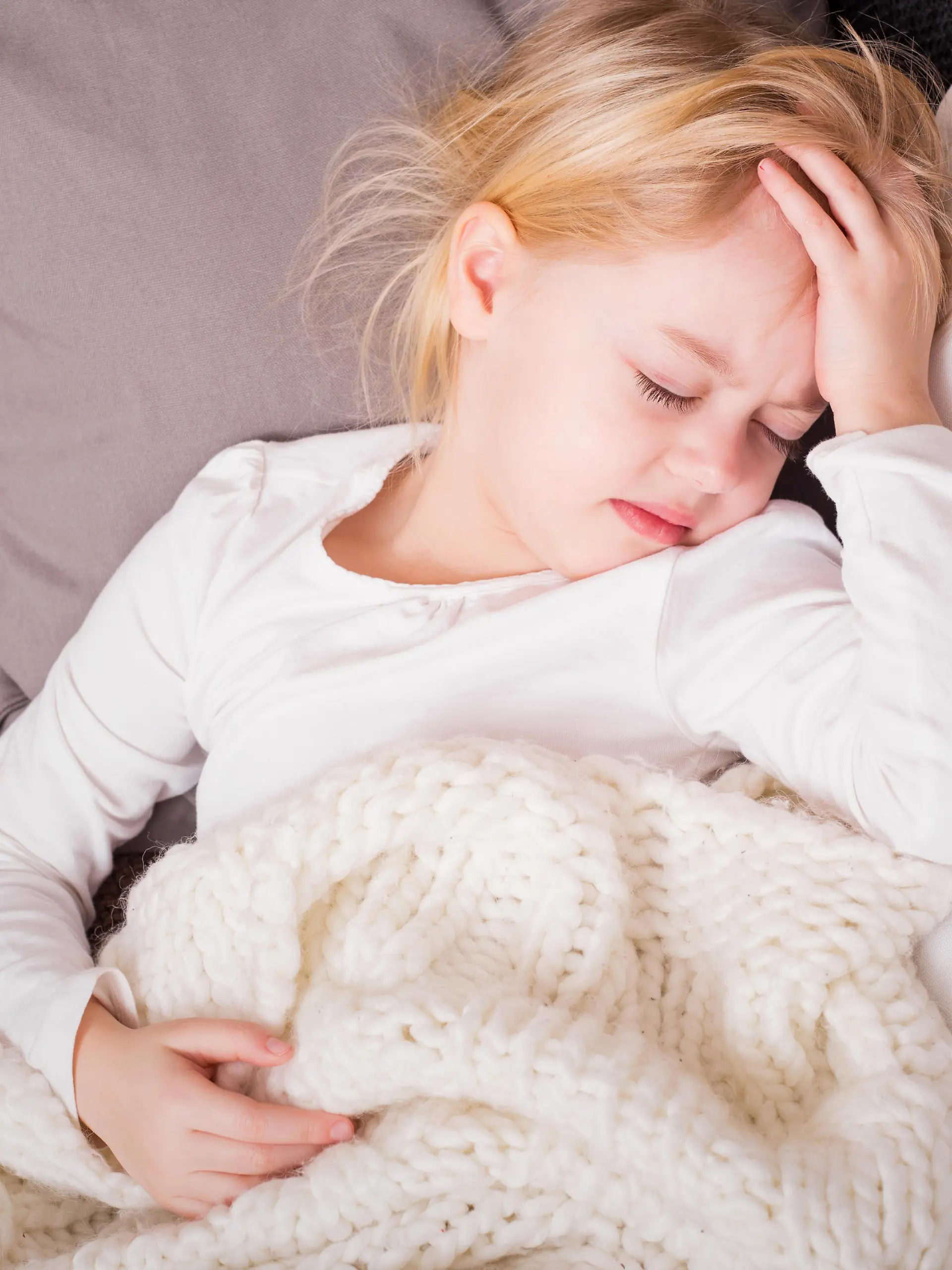 Little child being sick and holding her hand pressed against her forehead