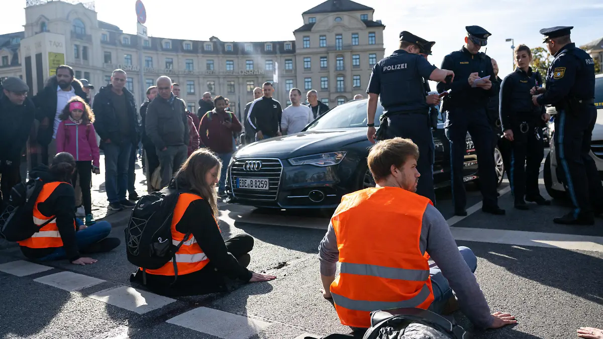 03.11.2022, Bayern, München: Klimaaktivisten haben sich am Karlsplatz in der Münchner Innenstadt auf die Fahrbahn geklebt und blockieren die Straße. Foto: Lennart Preiss/dpa +++ dpa-Bildfunk +++