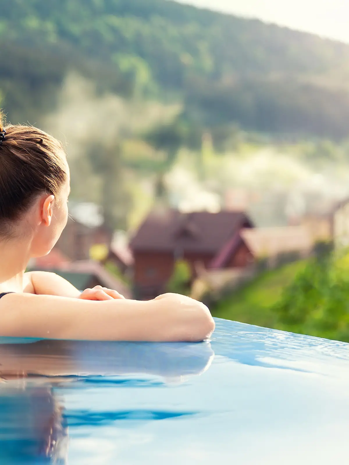 Frau, die in einem Pool mit Aussicht auf eine Berglandschaft entspannt.