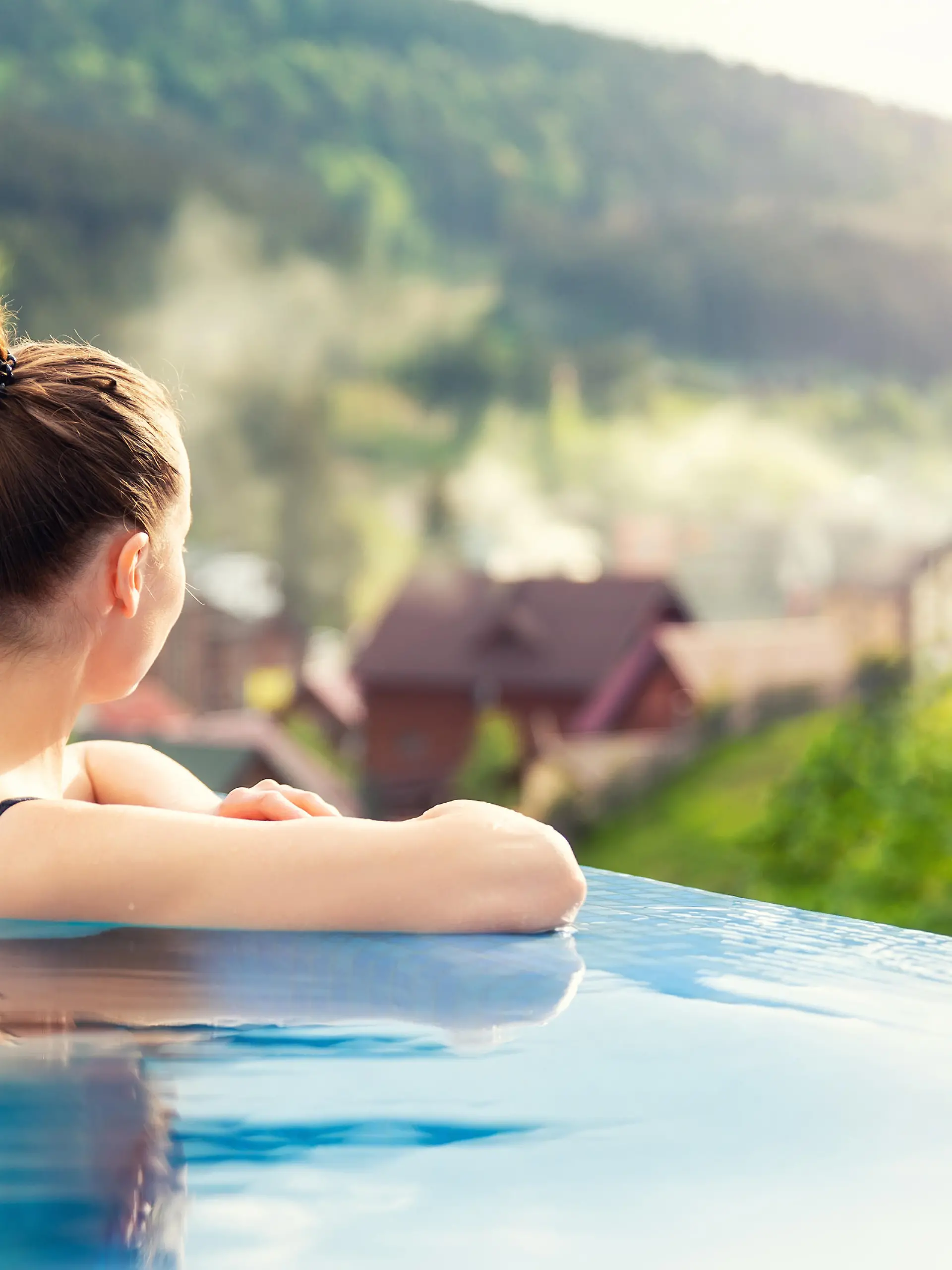 Frau, die in einem Pool mit Aussicht auf eine Berglandschaft entspannt.
