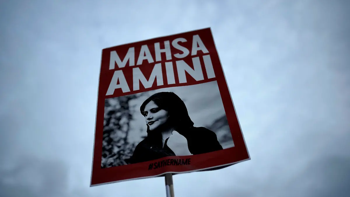 FILE - A woman holds a placard with a picture of Iranian woman Mahsa Amini during a protest against her death, in Berlin, Germany, on Sept. 28, 2022. A court in Iran sentenced two female journalists to up to seven years in prison for “collaborating” with the United States government among other charges, local reports said Sunday, Oct. 22, 2023. Both have been imprisoned for over a year following their coverage of the death of Mahsa Amini while in police custody in September 2022. (AP Photo/Markus Schreiber, File)