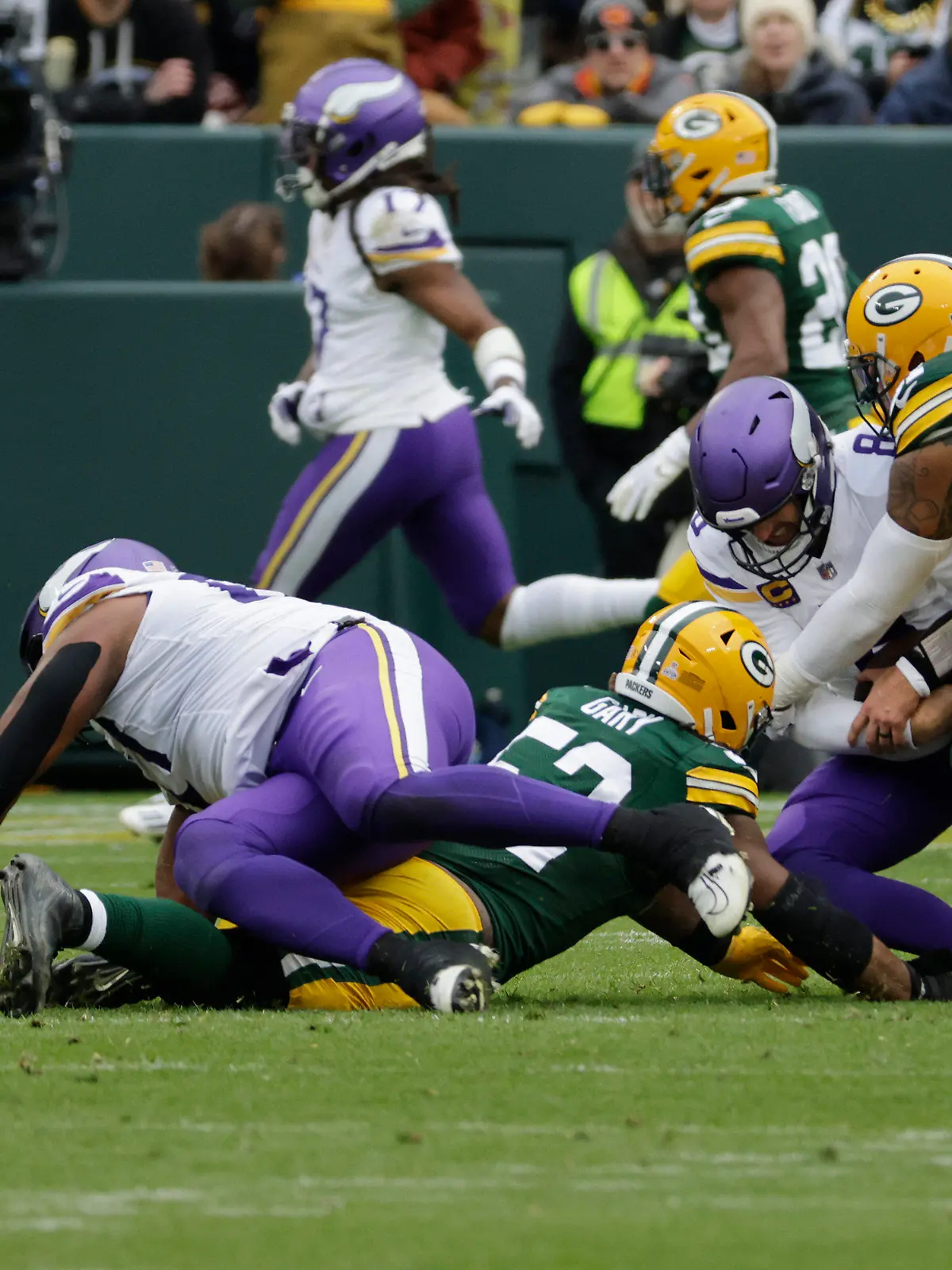 Minnesota Vikings quarterback Kirk Cousins (8) is tackled by Green Bay Packers linebacker Rashan Gary (52), middle left, and linebacker Preston Smith (91), right, during the second half of an NFL football game Sunday, Oct. 29, 2023, in Green Bay, Wis. (AP Photo/Mike Roemer)