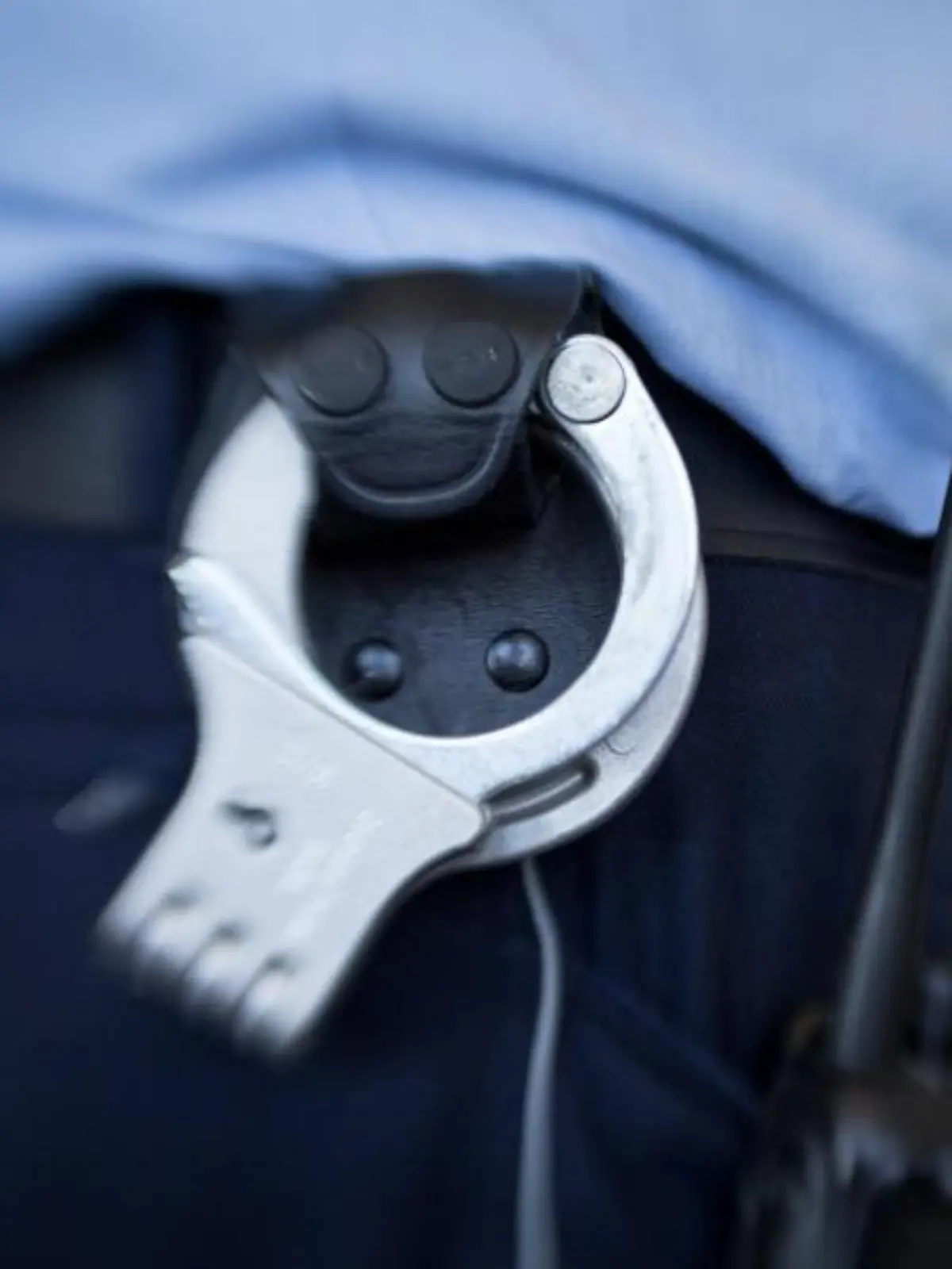Handschellen hängen am Gürtel eines Justizbeamten