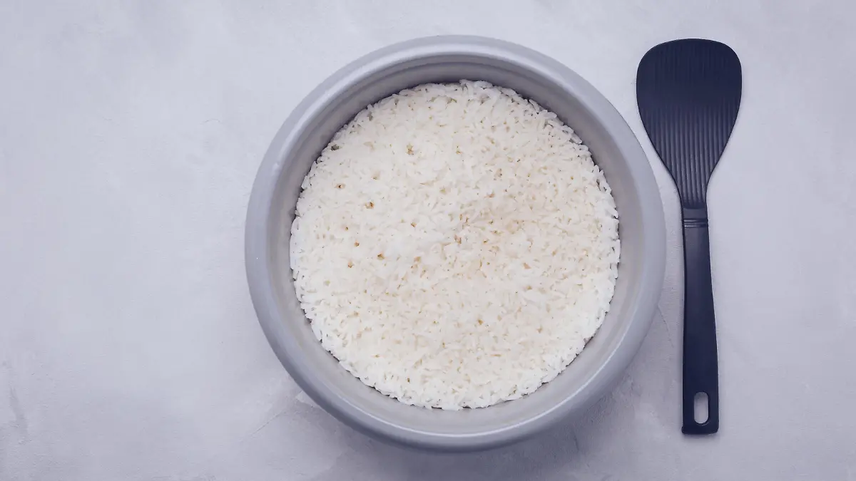 Rice in rice cooker or steamer with spoon, top view