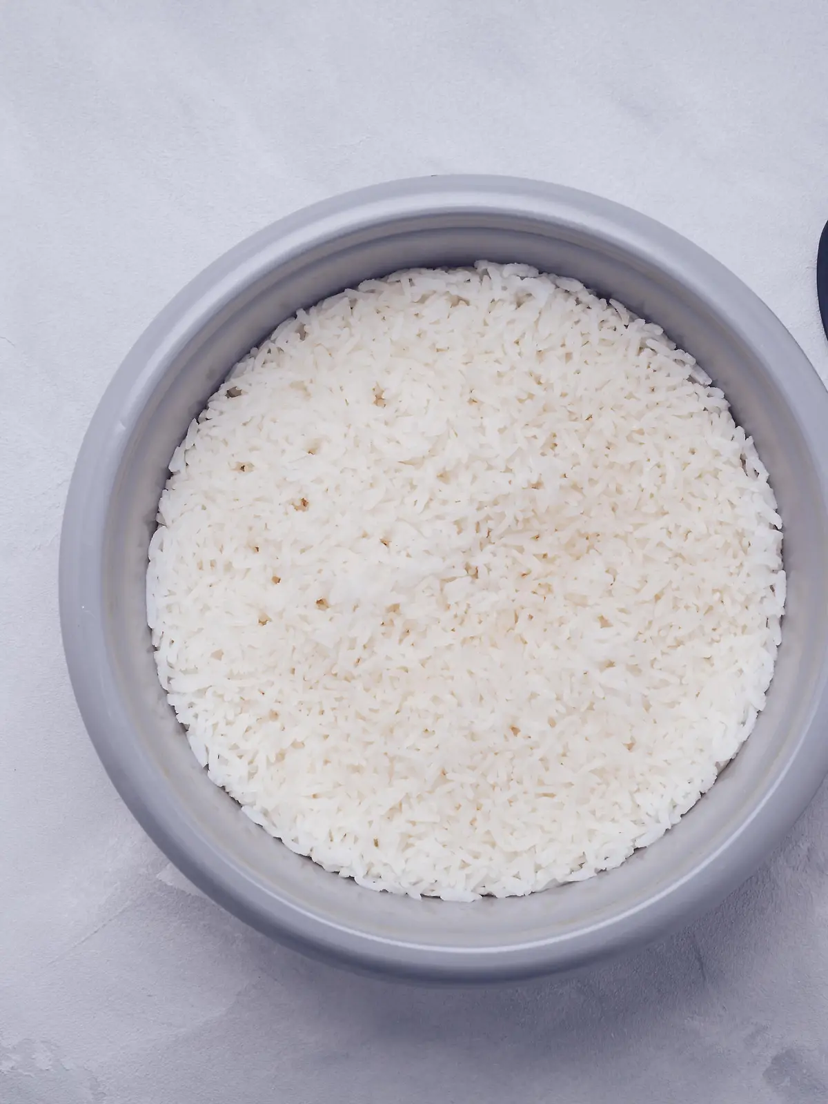 Rice in rice cooker or steamer with spoon, top view