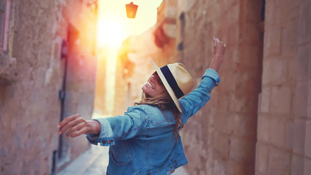 Frau mit einem Sonnenhut, die durch die Altstadt von Malta läuft.