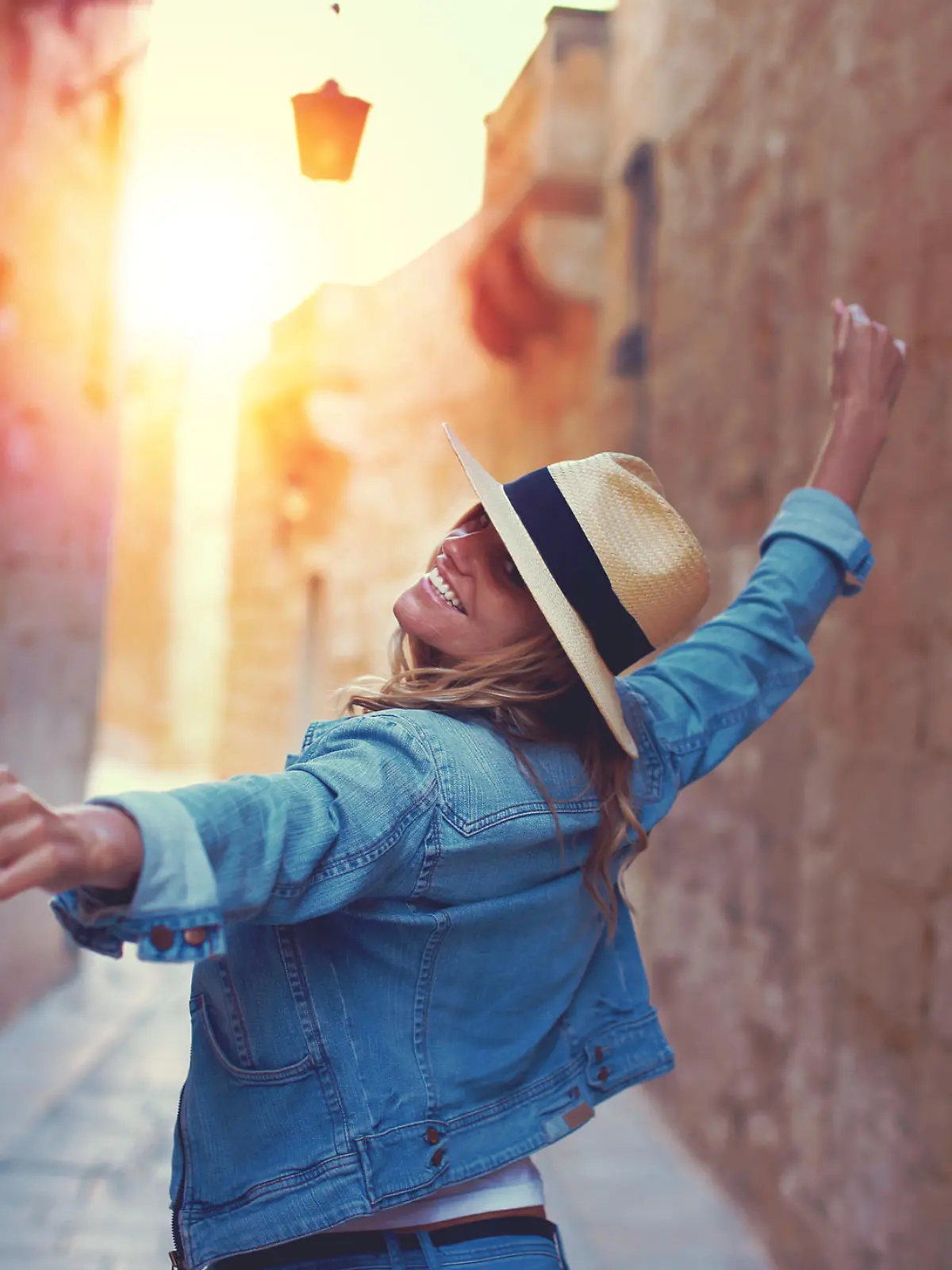 Frau mit einem Sonnenhut, die durch die Altstadt von Malta läuft.