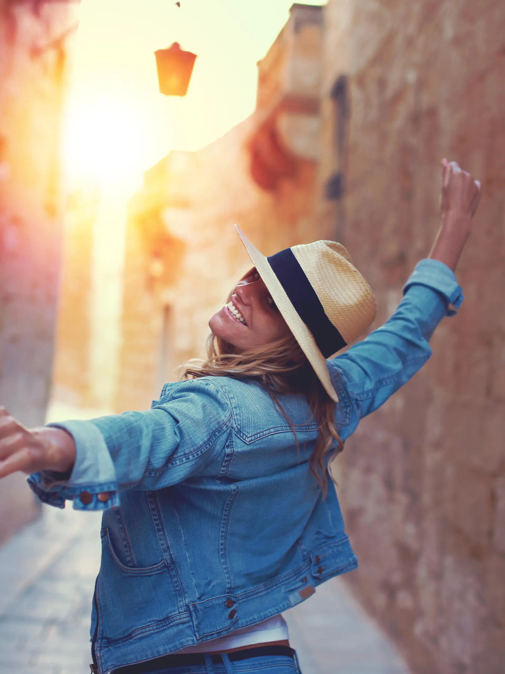 Frau mit einem Sonnenhut, die durch die Altstadt von Malta läuft.
