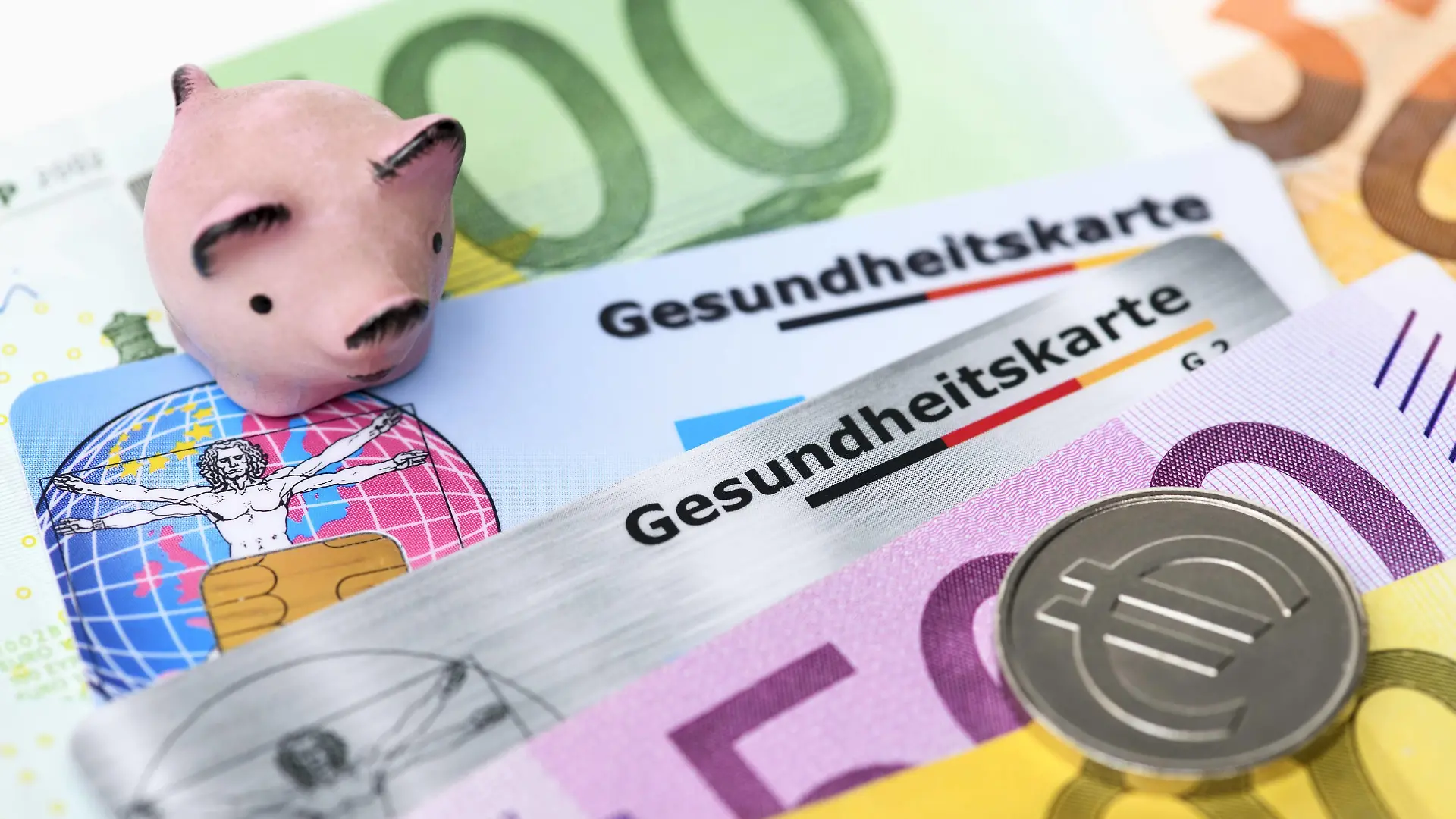Gesundheitskarten mit Geldscheinen und Sparschwein, Krankenkassenbeiträge *** Health cards with money and piggy bank health insurance contributions