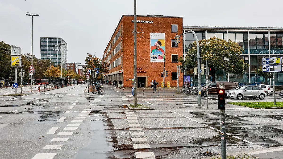 19.10.2023, Schleswig-Holstein, Kiel: Regenpfützen sammeln sich auf der Kreuzung vor dem Neuen Kieler Rathaus auf der sich ein schwerer Unfall ereignet hat. Die dabei tödlich verletzte Frau hatte nach neuen Erkenntnissen schon vorher schwere Verletzungen erlitten. Die Polizei ermittelt deshalb wegen eines Tötungsdeliktes, wie sie am Donnerstag in Kiel mitteilte. Foto: Axel Heimken/dpa +++ dpa-Bildfunk +++