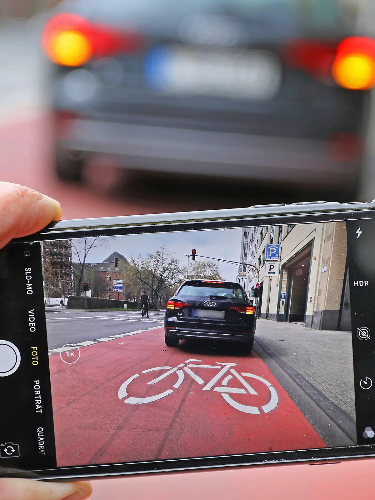 ILLUSTRATION - 16.04.2021, Nordrhein-Westfalen, Köln: ARCHIV - Auf einem Smartphone ist das Bild eines Autos zu sehen, das auf einem Radfahrstreifen hält. (zu dpa: «Prozess: Dürfen Bürger Falschparker für Anzeige fotografieren?») Foto: Oliver Berg/dpa - ACHTUNG: Kfz-Kennzeichen wurde aus persönlichkeitsrechtlichen Gründen gepixelt +++ dpa-Bildfunk +++