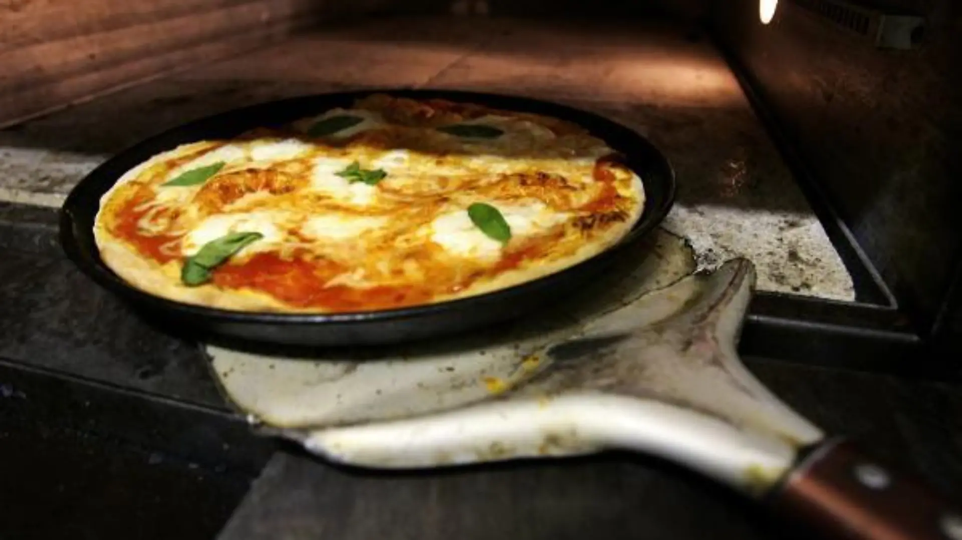 Ein Pizzabäcker holt mit einem Schieber eine frisch zubereitete typische Pizza Margherita, belegt mit Mozarella und Basilikum, aus einem Pizzaofen in Frankfurt am Main (Foto vom 17.01.2008). Was als "Straßenkind" die Karriere begann und an jeder Ecke für ein paar Münzen feilgeboten wurde, trat einen Siegeszug um die ganze Welt an. Neapel gilt als Welthauptstadt der Pizza und legt Wert darauf, im 18. Jahrhundert die einzig wahre Version, die "la vera pizza napoletana" kreiert zu haben. Ein verstaubtes Kirchendokument von 1535 erwähnt diese Art Kuchen oder Teigwaffel. Foto: Arno Burgi dpa (zu dpa-Reportage: 'Die Pizza, Neapels Wunderrad - Das "Straßenkind" mit Weltkarriere' vom 21.01.2008) +++(c) dpa - Bildfunk+++