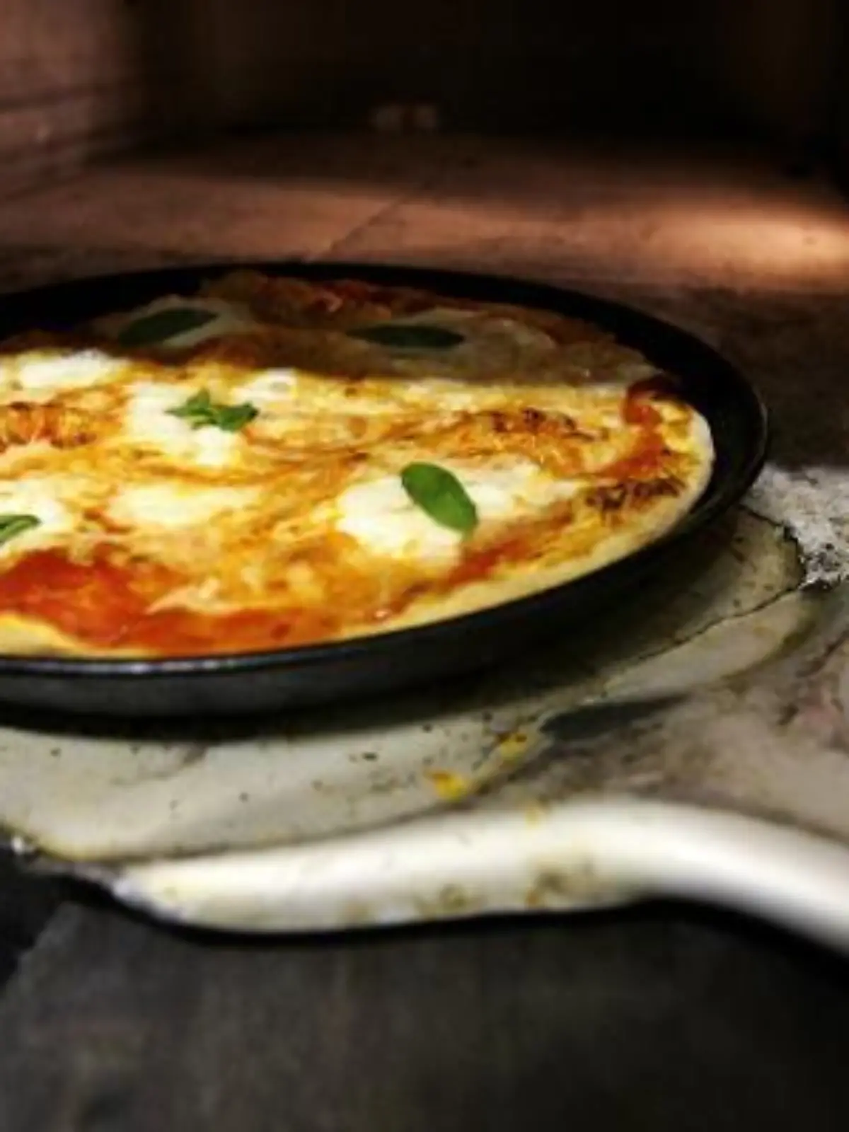 Ein Pizzabäcker holt mit einem Schieber eine frisch zubereitete typische Pizza Margherita, belegt mit Mozarella und Basilikum, aus einem Pizzaofen in Frankfurt am Main (Foto vom 17.01.2008). Was als "Straßenkind" die Karriere begann und an jeder Ecke für ein paar Münzen feilgeboten wurde, trat einen Siegeszug um die ganze Welt an. Neapel gilt als Welthauptstadt der Pizza und legt Wert darauf, im 18. Jahrhundert die einzig wahre Version, die "la vera pizza napoletana" kreiert zu haben. Ein verstaubtes Kirchendokument von 1535 erwähnt diese Art Kuchen oder Teigwaffel. Foto: Arno Burgi dpa (zu dpa-Reportage: 'Die Pizza, Neapels Wunderrad - Das "Straßenkind" mit Weltkarriere' vom 21.01.2008) +++(c) dpa - Bildfunk+++