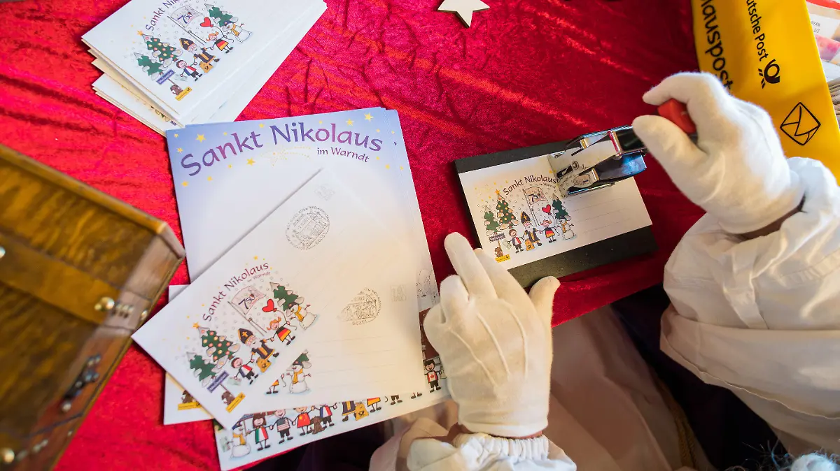 ARCHIV - 05.12.2020, Saarland, St. Nikolaus: Der Nikolaus stempelt in der Nikolaushütte beim Nikolauspostamt im saarländischen St. Nikolaus einen Brief ab. (zu dpa «Kinder wünschen sich Frieden vom Nikolaus») Foto: Oliver Dietze/dpa +++ dpa-Bildfunk +++