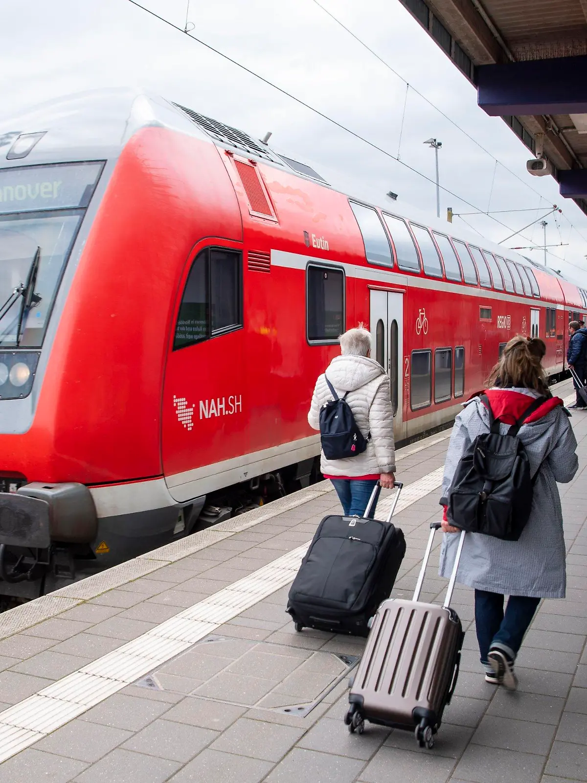 ARCHIV - 27.04.2023, Niedersachsen, Norddeich: Touristen laufen mit Rollkoffern am Bahnhof Norddeich-Mole entlang. (zu dpa «Halbes Jahr Deutschlandticket - hohe Nachfrage in Niedersachsen») Foto: Philip Dulian/dpa +++ dpa-Bildfunk +++