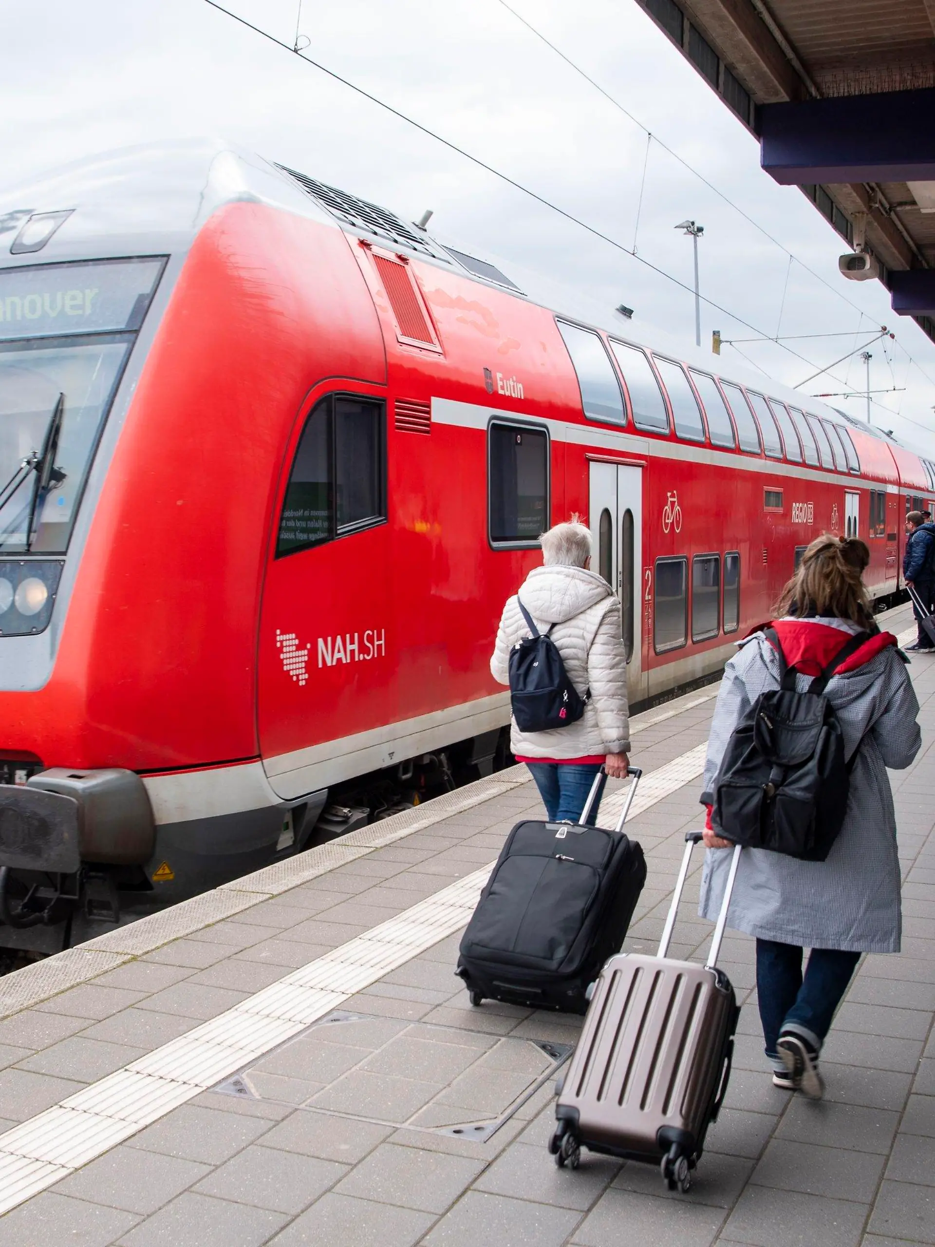 ARCHIV - 27.04.2023, Niedersachsen, Norddeich: Touristen laufen mit Rollkoffern am Bahnhof Norddeich-Mole entlang. (zu dpa «Halbes Jahr Deutschlandticket - hohe Nachfrage in Niedersachsen») Foto: Philip Dulian/dpa +++ dpa-Bildfunk +++