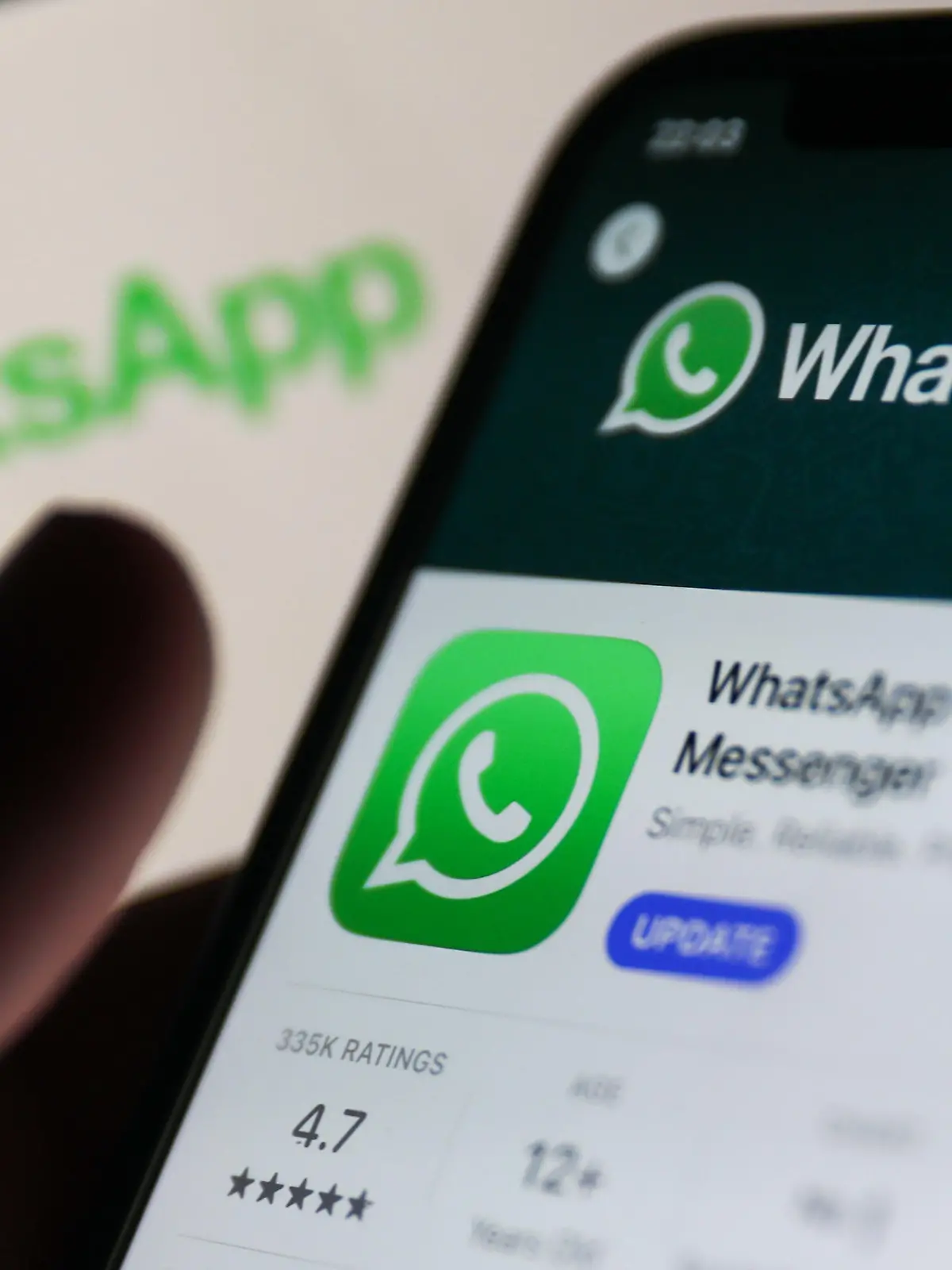 WhatsApp on App Store displayed on a phone screen and WhatsApp logo displayed on a screen in the background are seen in this illustration photo taken in Krakow, Poland on Auguust 13, 2023. (Photo by Jakub Porzycki/NurPhoto)