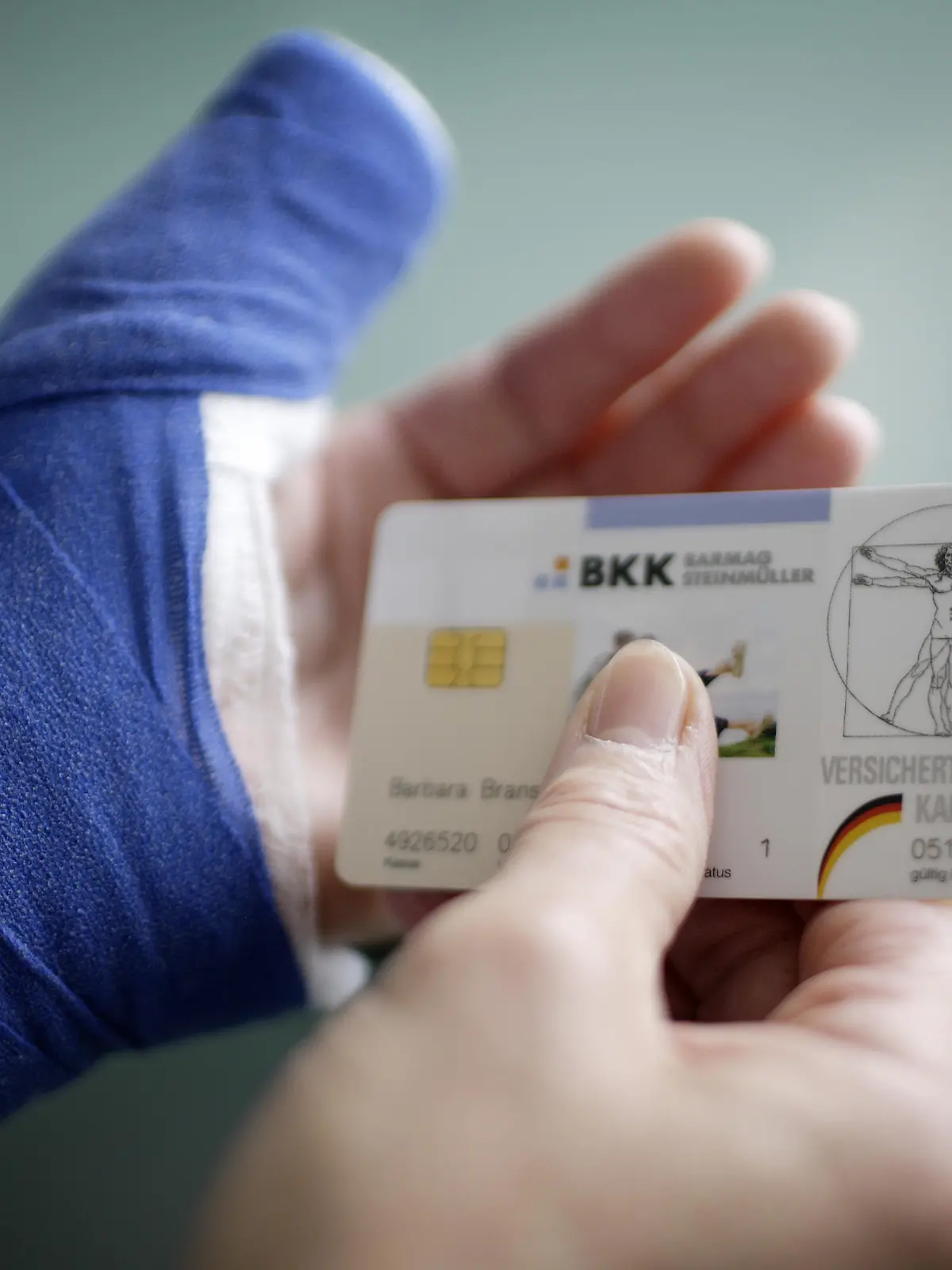 Eine Frau mit verletztem Arm und Gesundheitskarte . Berlin , Deutschland . | Woman with broken arm holding a health insurance card . Berlin , Germany . | 05.06.2008 , MODEL RELEASE vorhanden , MODEL RELEASED , Copyright: Thomas Imo/ picture alliance/photothek